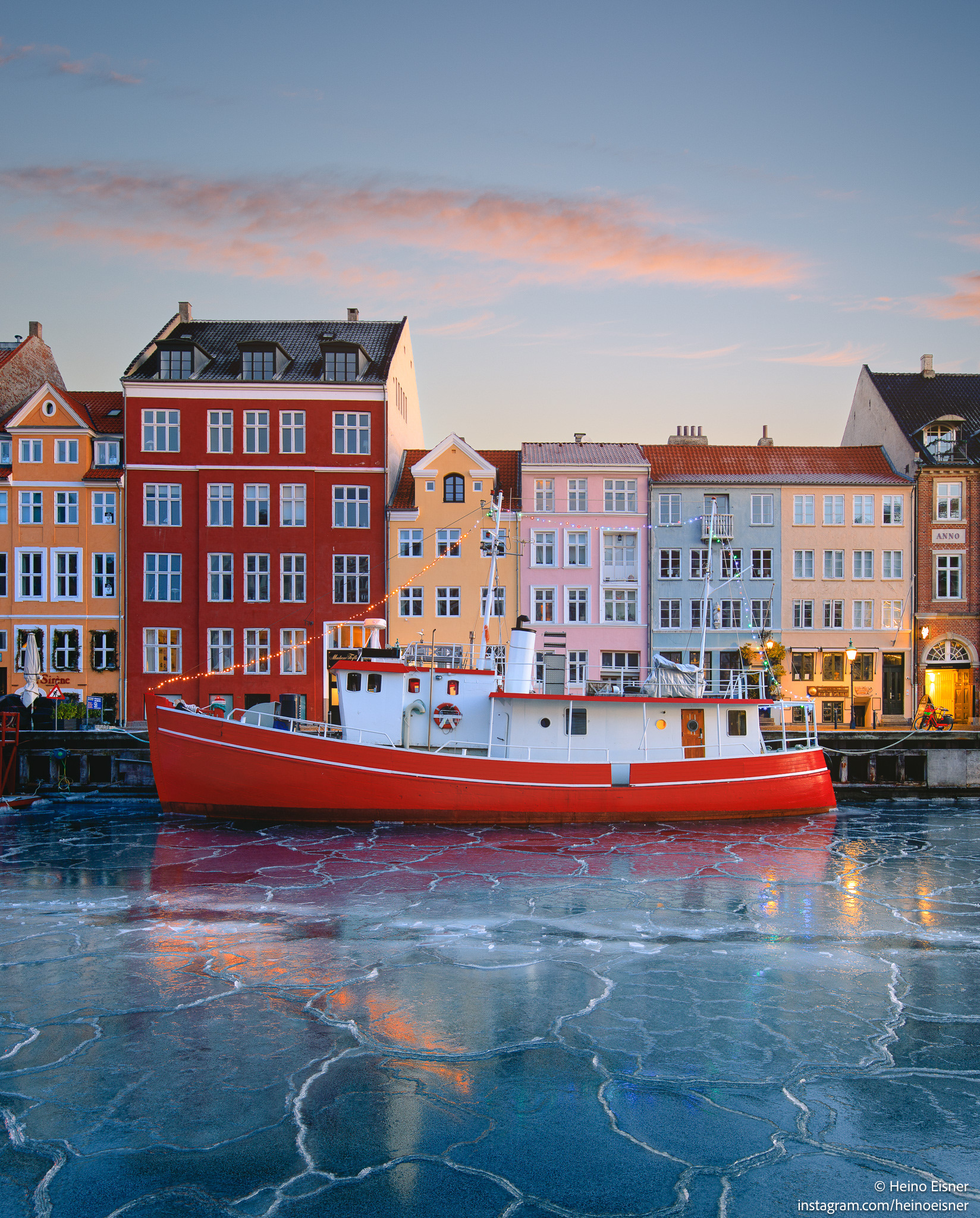 Nyhavn during winter, with ice on the water and a red boat and colourful houses