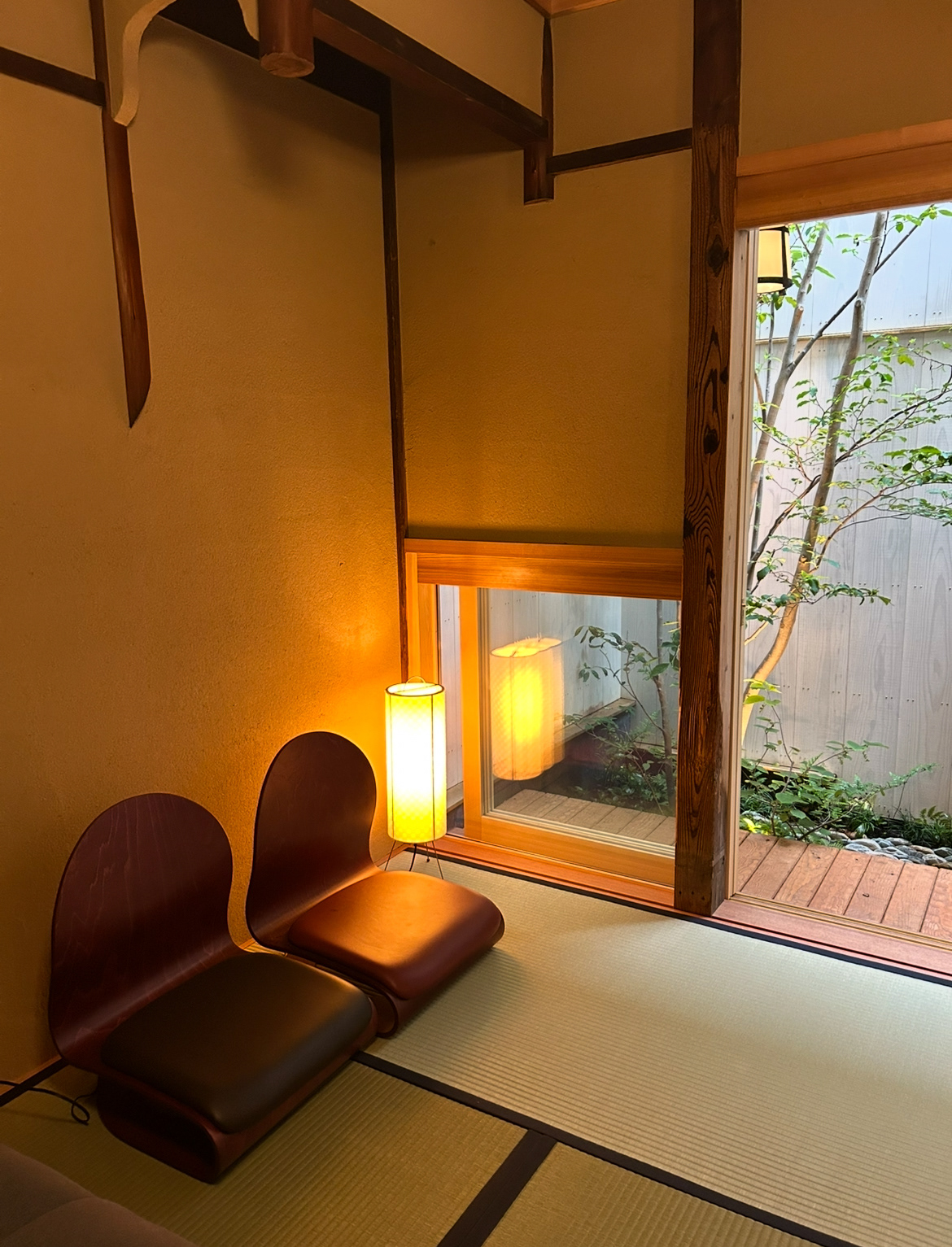 Tatami mat seating area looking into a small tsuboniwa at a micro-hotel in Kyoto.