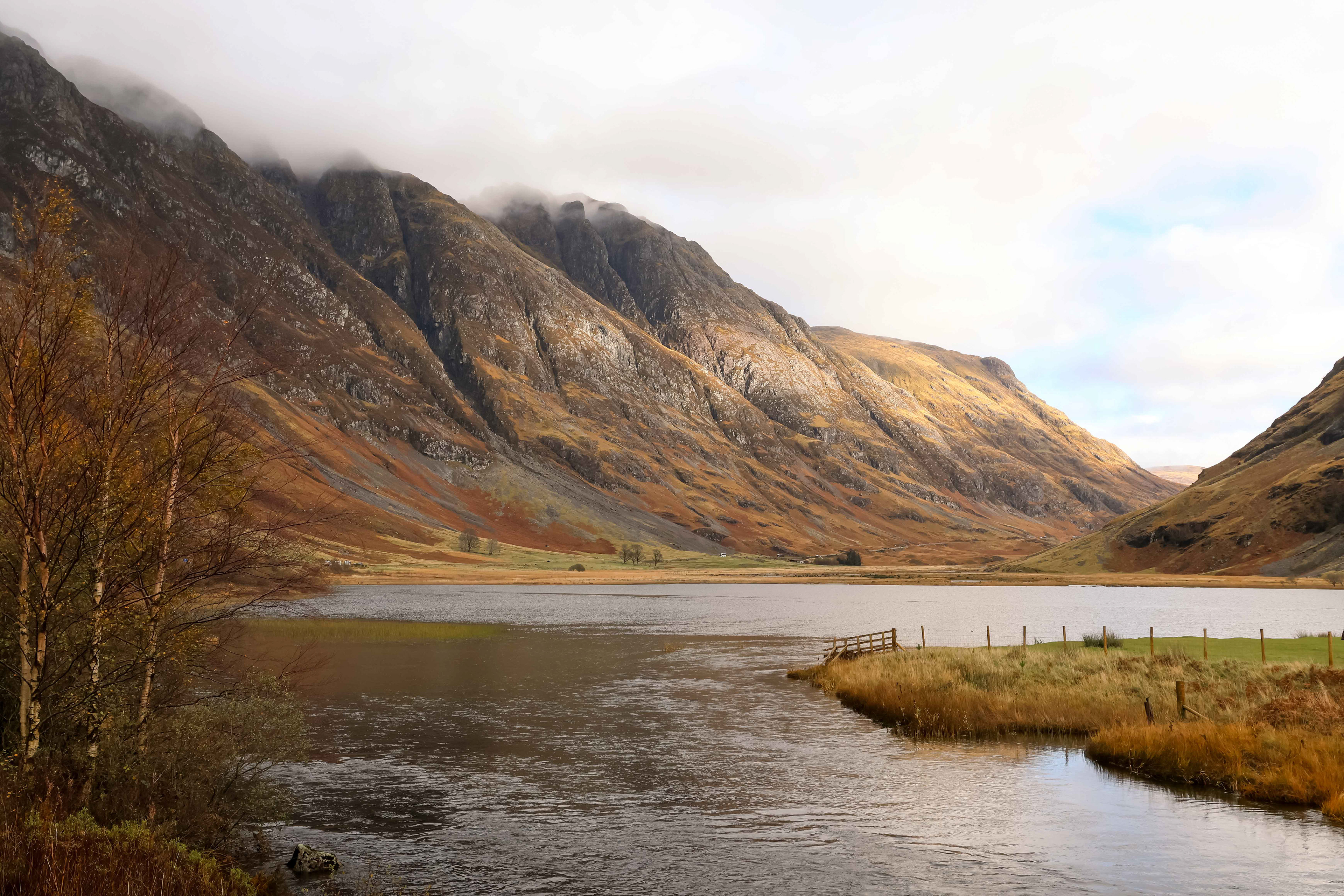 a landscape of steep mountain peaks reflected in a calm lake, scotland