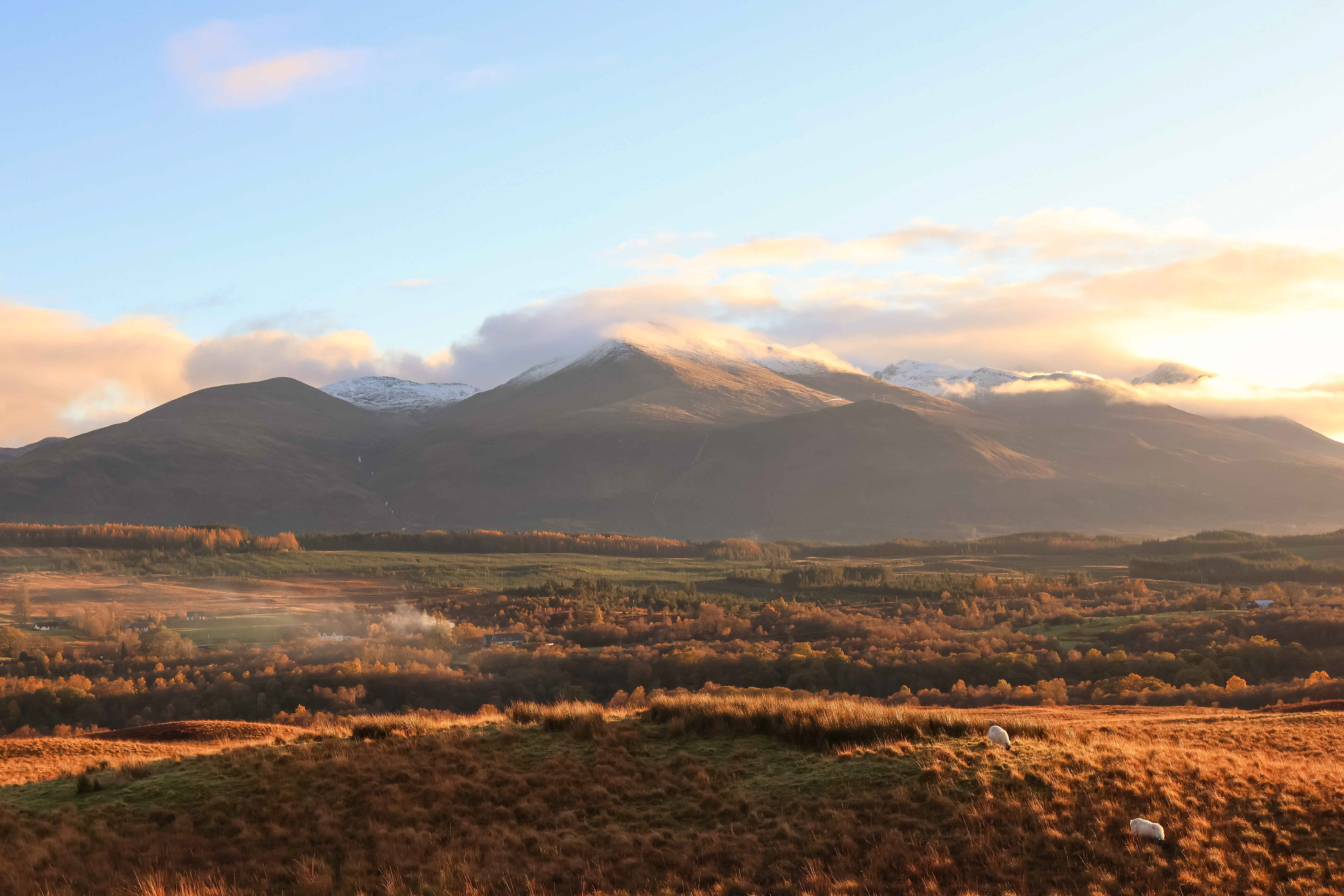 first snow on the highland peaks, bathed in the warmth of the golden hour, scotland