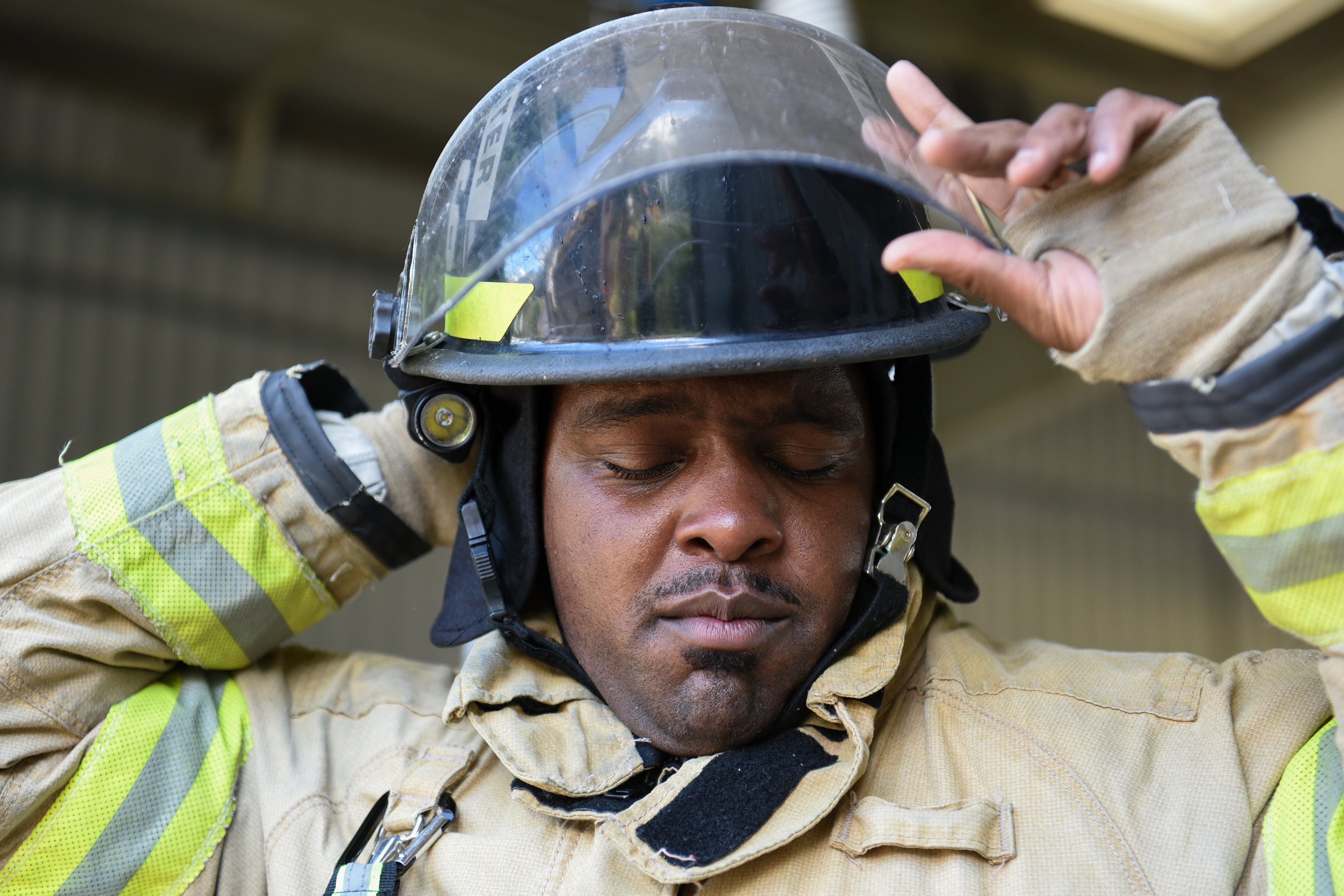 Justin Martin puts on his helmet on Friday during training outside Fire Station 3 in Columbus. Martin has been a firefighter for three years.