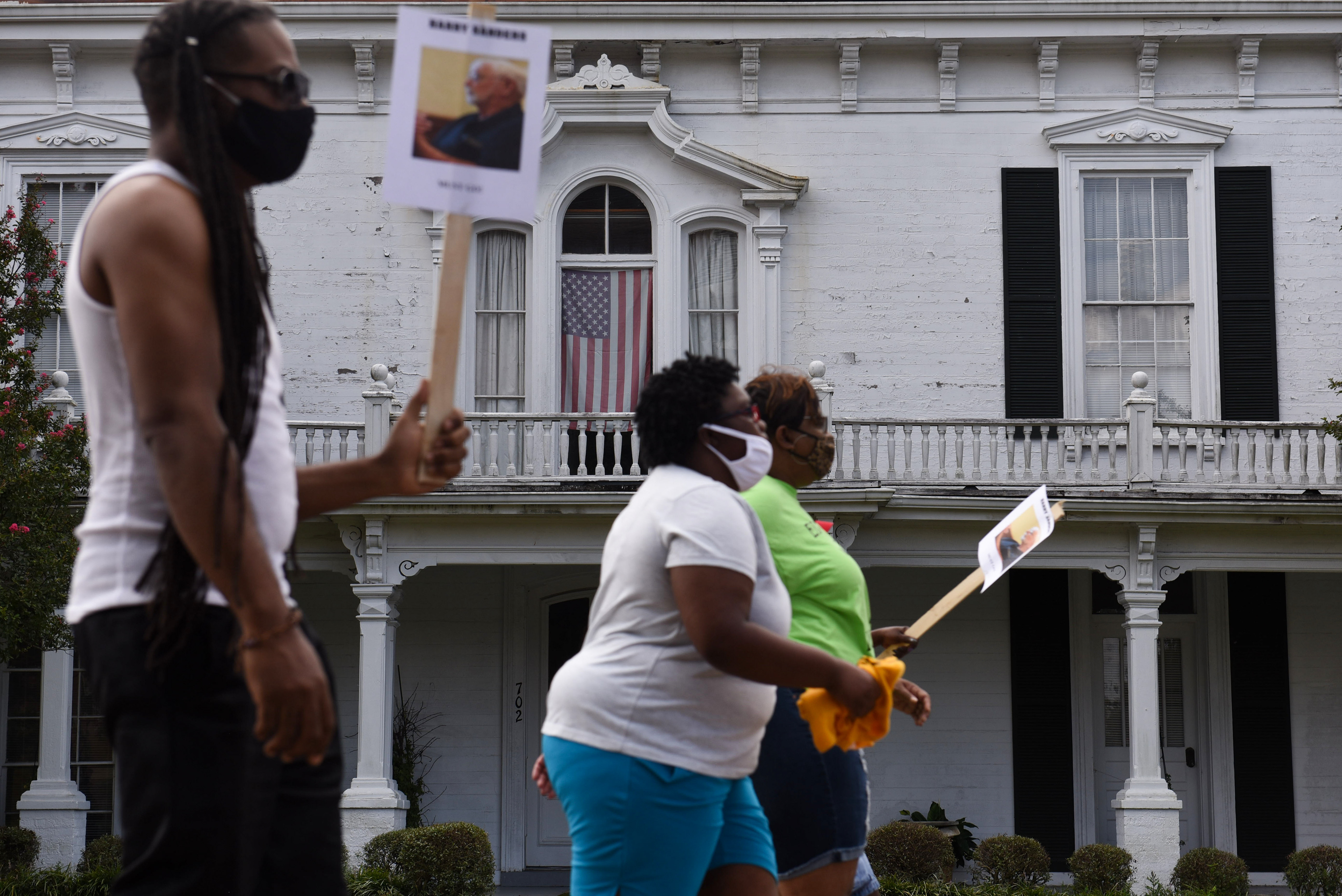 An American flag hangs in a window as protesters march past it during the Equality and Justice March on Saturday, August 1 in Columbus. The march and rally lasted about an hour and a half.
