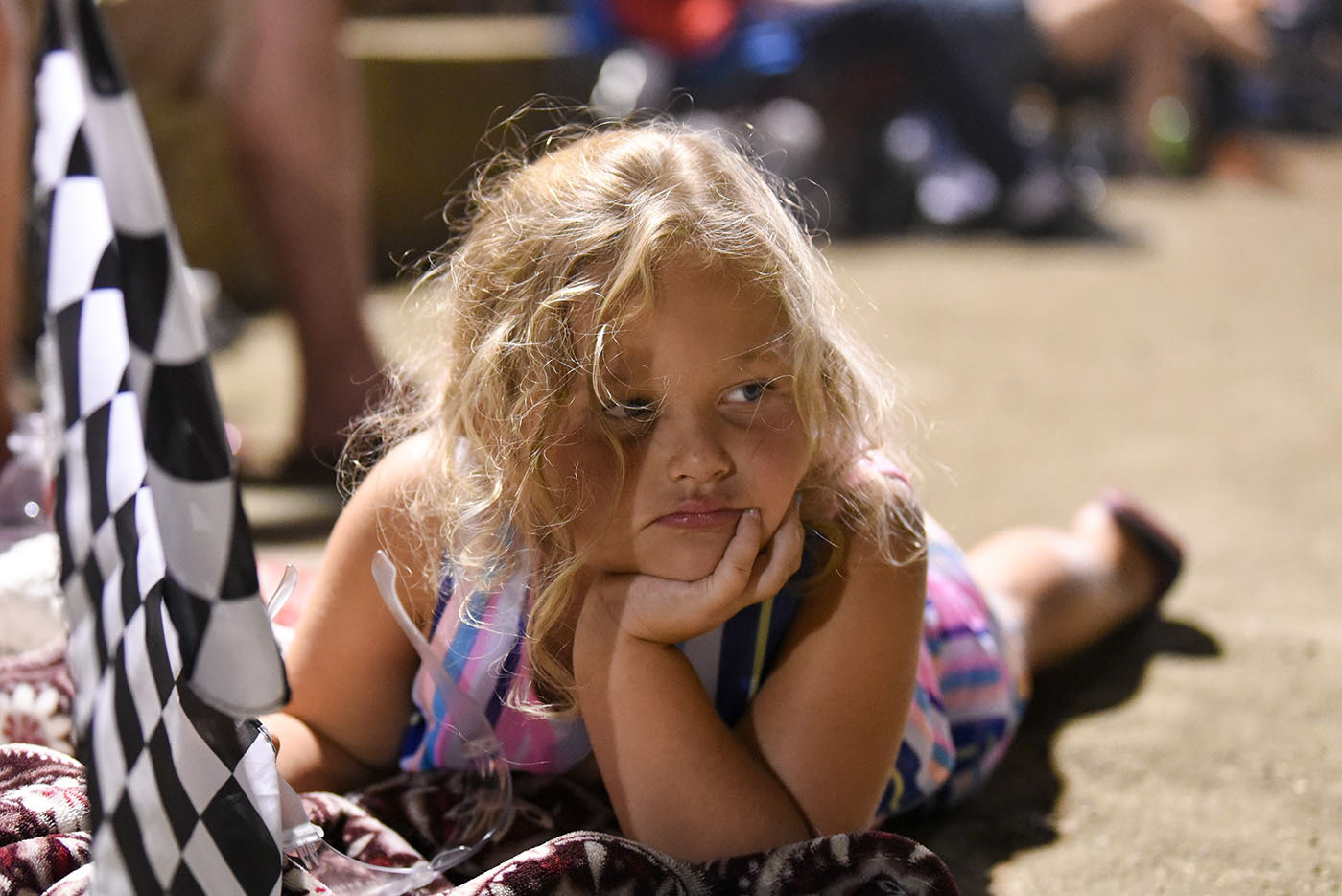 Katie Jane Jones, 5, lies down on a blanket during the General Tire Clash at the Mag on June 20 at Magnolia Motor Speedway in Columbus. This was Katie Jane’s first time at the racetrack, and she said it was kind of boring, but she entertained herself by waving her flag around.