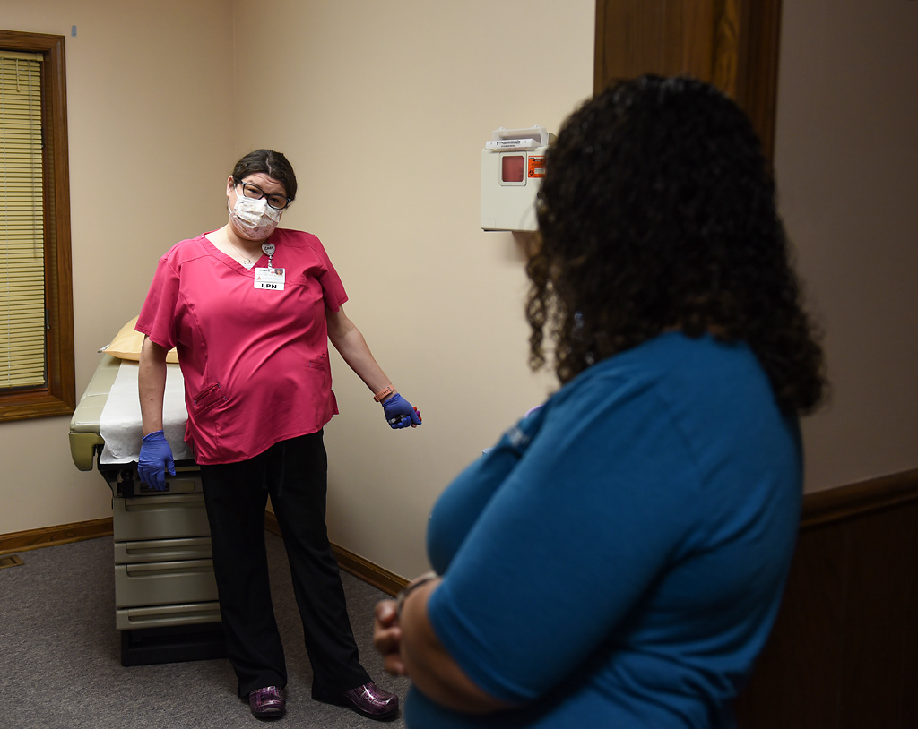 From left, Ciaira Cain, a practical nurse, speaks with Sarah Kirchhoff after doing blood tests for a patient on Tuesday, April 28, 2020 at the Western Missouri Family Healthcare clinic in Concordia. When patients come into the clinic for appointments, the clinic staff, which consists of Kirchhoff, Cain, a nurse practitioner and a receptionist, wears masks, goggles and gloves. They also try to schedule appointments so that routine check-ups and procedures are in the morning and patients who are sick come in the afternoon.