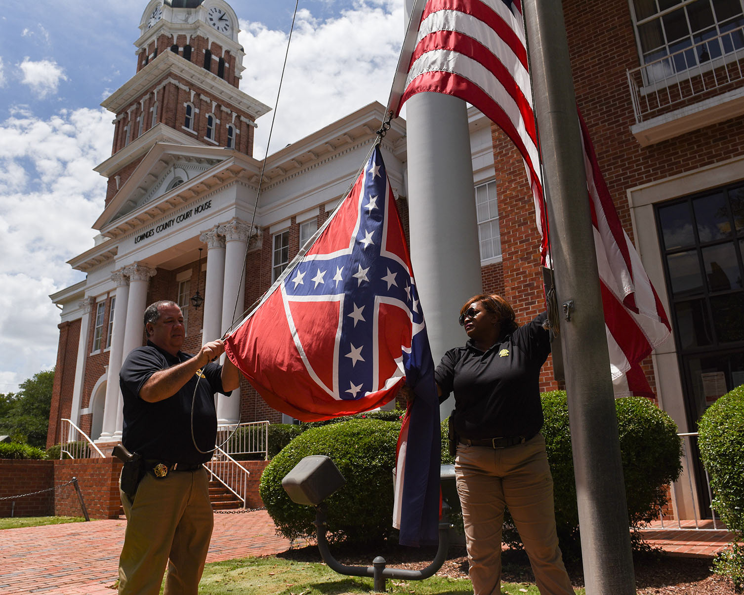 Lowndes County Sheriff Eddie Hawkins unclips the state flag- which displays the Confederate battle emblem in its left corner- while Lt. Rhonda Sanders holds it on Monday, June 29 afternoon at the Lowndes County Courthouse. The Senate voted 37-14 to retire the flag and the House voted 91-23 on Sunday.