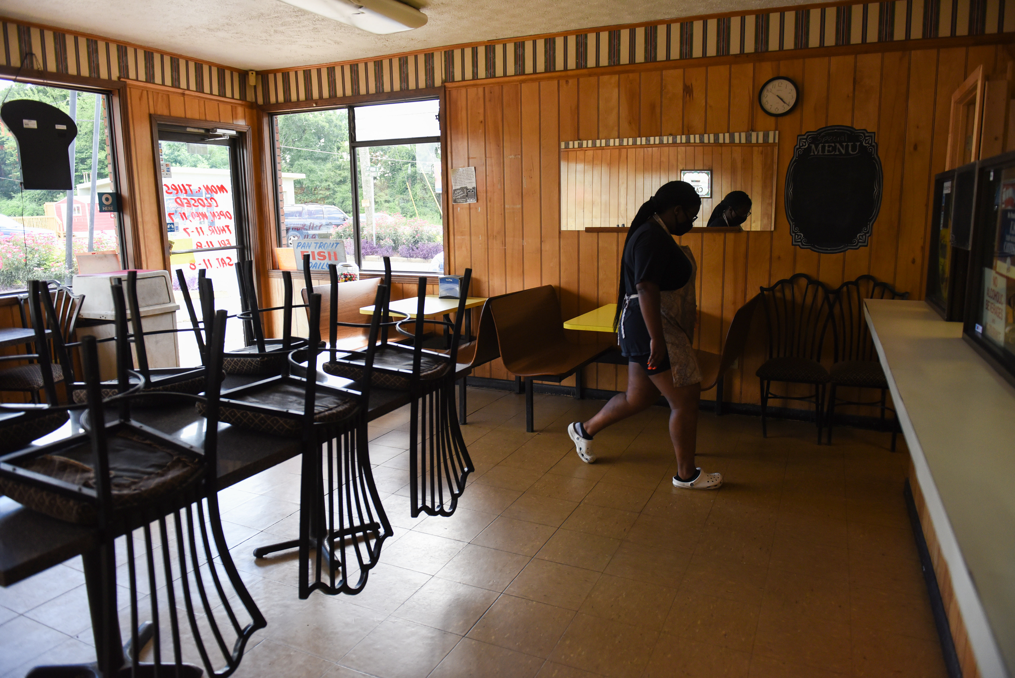 Carolena Graham, 16, walks through the empty dining room back to the kitchen after bringing out a curbside pickup order on Friday at Skeet’s Hotdogs in Columbus. Sylvia Graham, owner of Skeet’s Hotdogs, said business has been steady throughout the pandemic, and she attributes that to people receiving unemployment and stimulus checks. But she also said that regular customers at her restaurant miss being able to sit in the dining room.