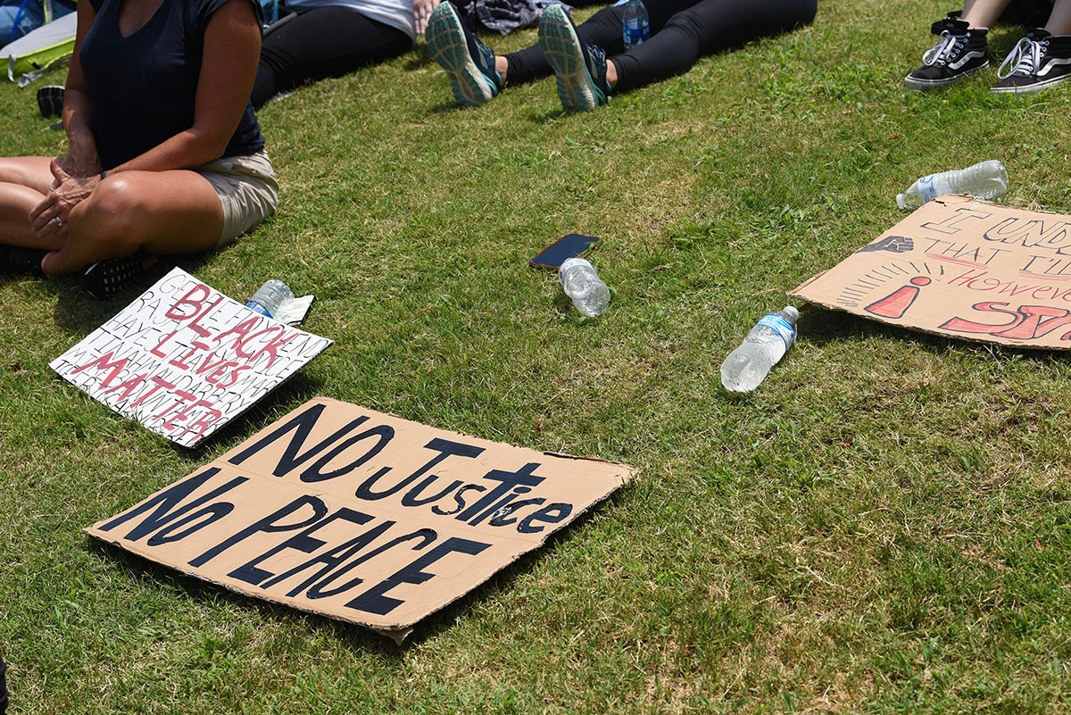 Signs, water bottles and a cellphone are scattered on the grass as people listen to speakers during the Starkville Stand Up Justice March on Saturday, June 6, 2020 at the Mississippi State Amphitheater. Organizers of the march set up shade tents with fans and volunteers passed out water bottles in an effort to keep everyone cool.