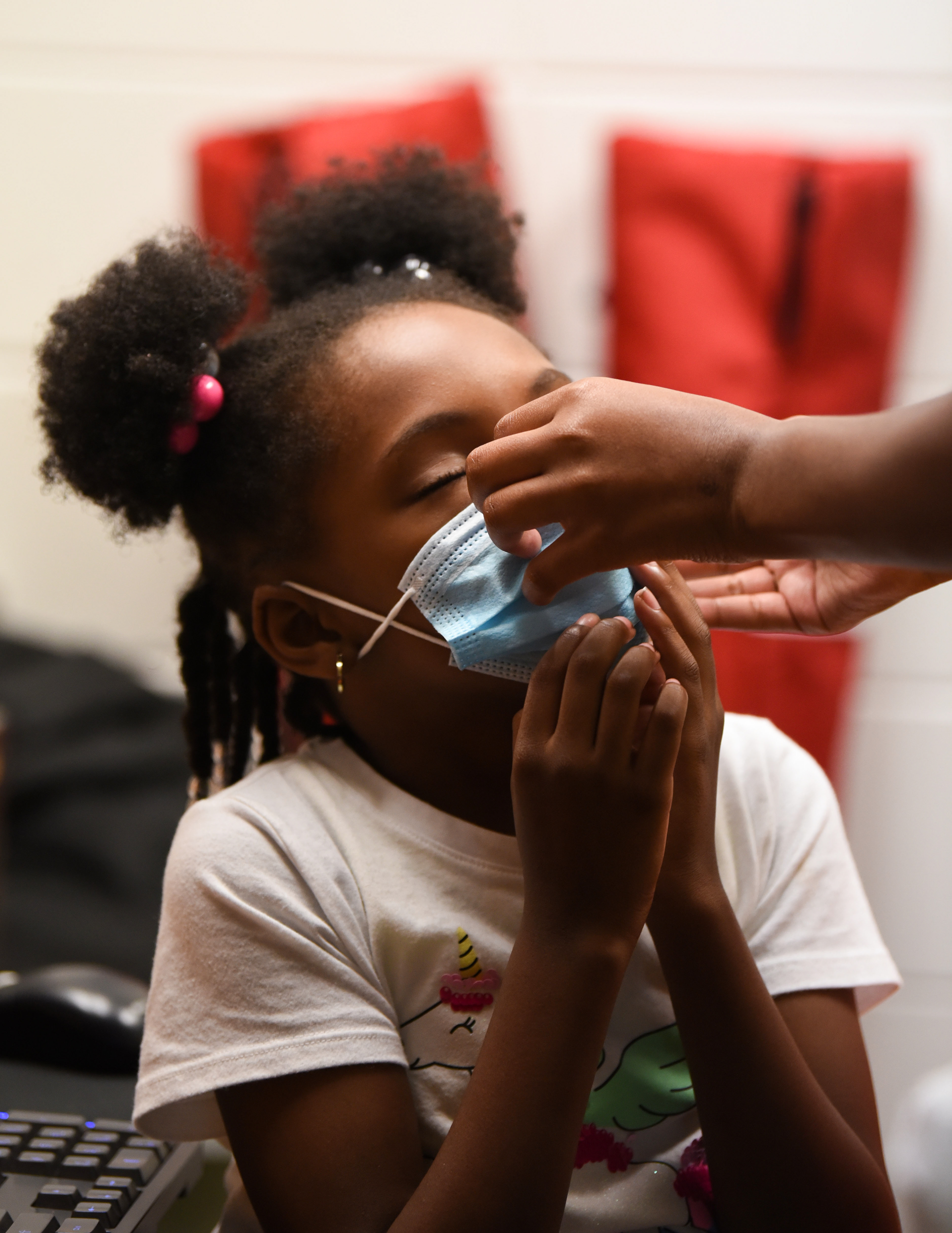 An older student helps Khloe Neely, 8, adjust her mask during Ms. Smith’s Academic Summer Camp on July 21 at the Needmore Center in Starkville. As precautions for COVID-19, everyone wore masks throughout the day, except during lunch time, and people received hand sanitizer and got their temperature checked as they entered the building each morning.