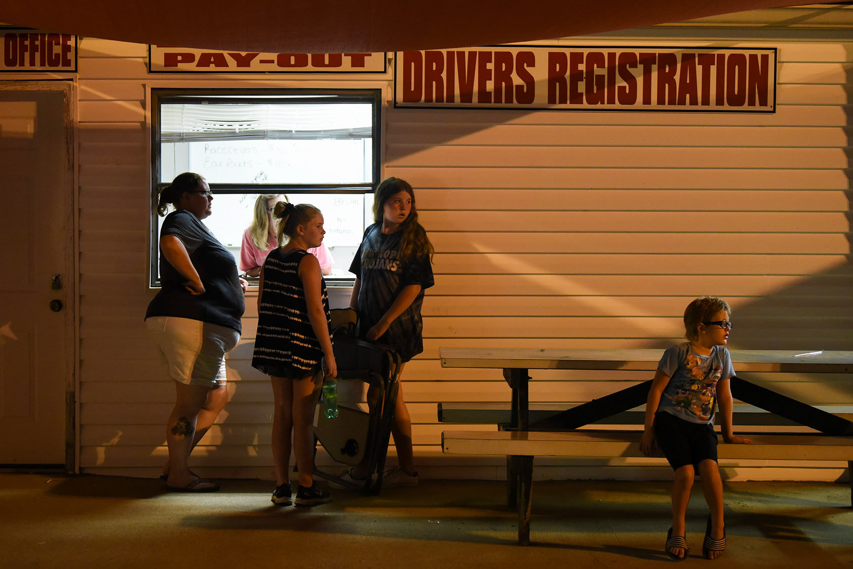 From left, Tammy Nowland, Sierra Knight, 12, Raeleigh Nowland, 12, and Lyam Nowland, 7, cluster outside the pay-out window while Daneen Carroll works on June 6 at Magnolia Motor Speedway in Columbus. Tammy has been running the gate at the track for the last 10 years, and she’s been bringing her daughter Raeleigh since Raeleigh was 2.