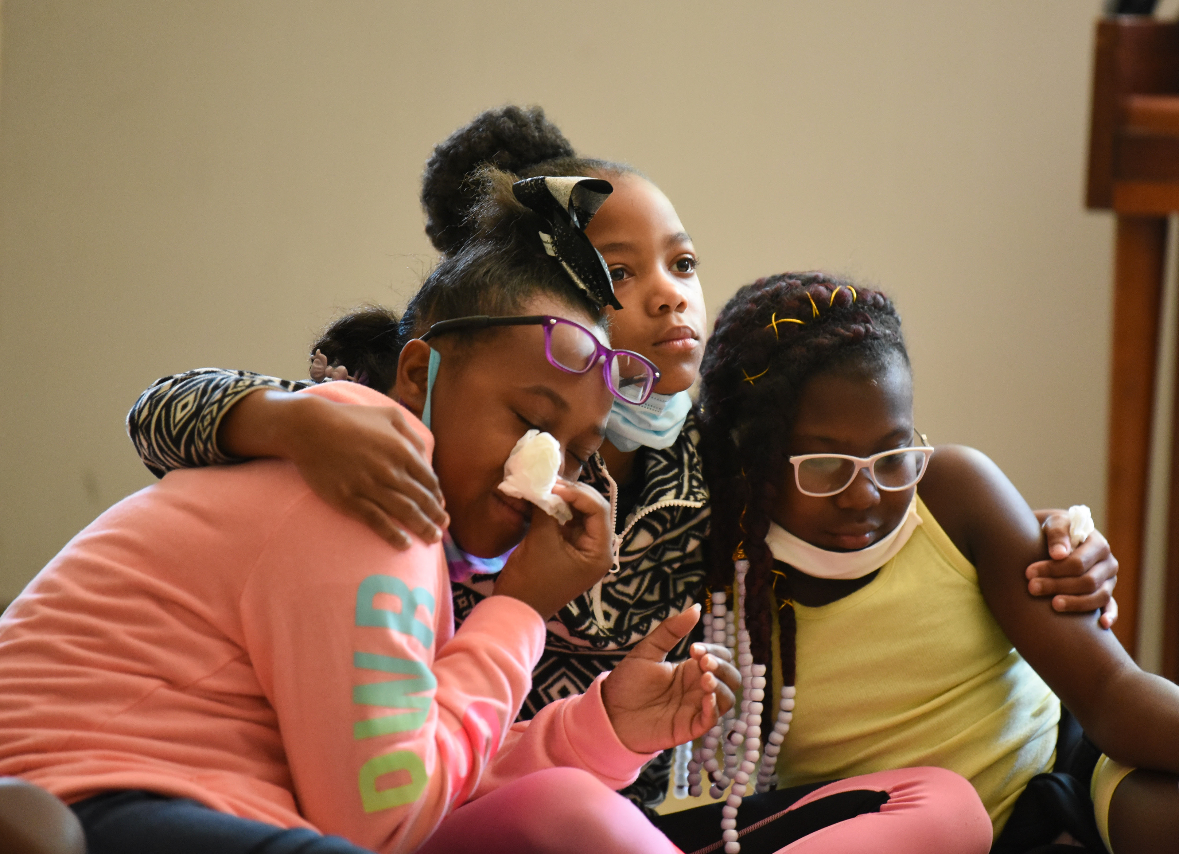 From left, Allyson Henley, 10, Alhyson Jett, 9, and Kylah Neely, 10, comfort each other and wait for prayers to conclude during Ms. Smith’s Academic Summer Camp on July 23 at the Needmore Center in Starkville. Community leaders led a prayer circle for the campers and then offered to pray for with the kids individually about anything that was on their minds. Allyson, Alhyson and Kylah each received prayers and then sat down together while the rest of their peers were prayed over.
