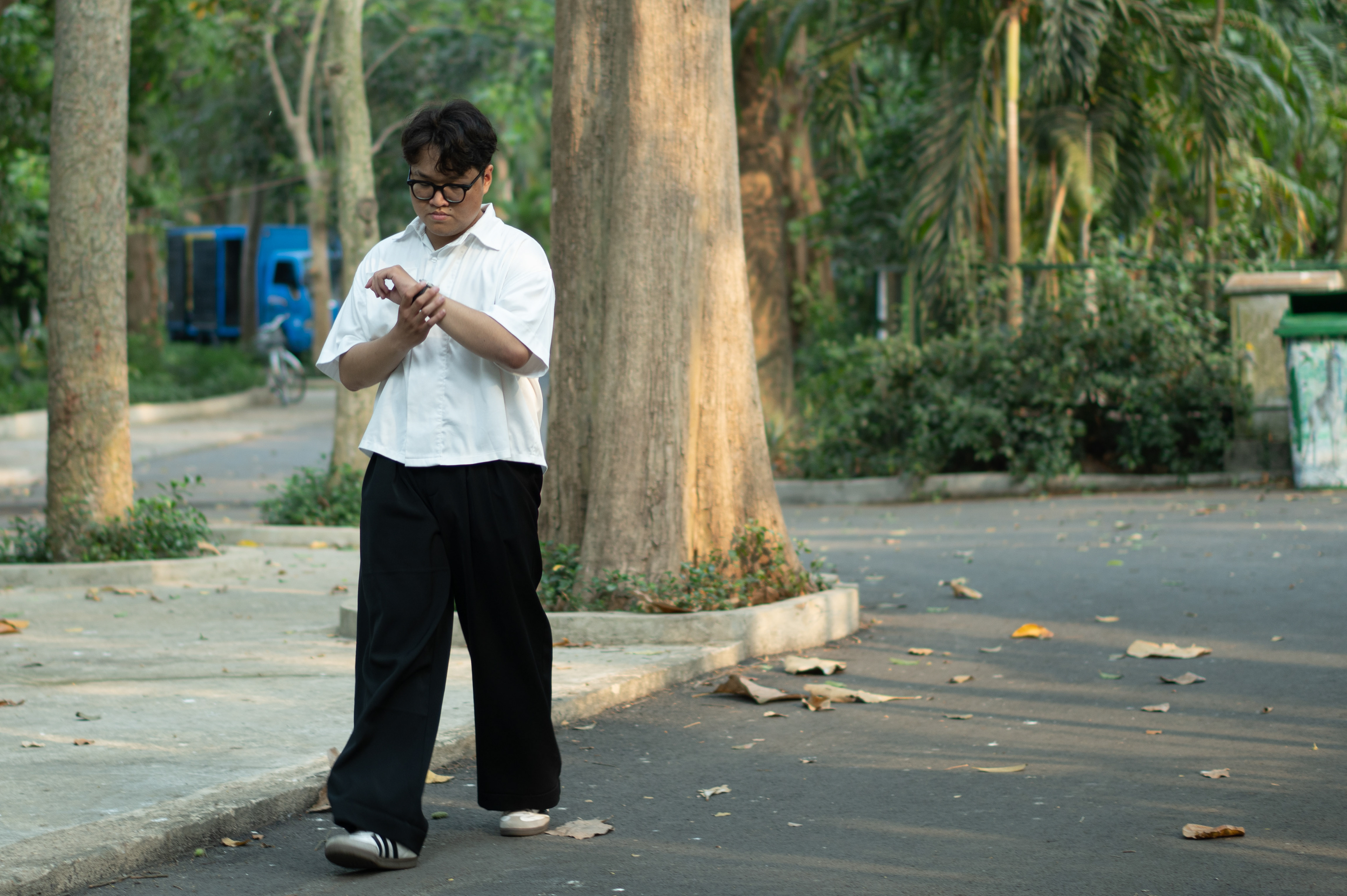 In the zoo, a visitor stands beside an animal enclosure. Their attention is momentarily diverted from the fascinating creatures within. With a furrowed brow, the visitor reaches down to adjust his outfit. With its blurred background, the animal enclosure hints at the reason for the visit, but adjusting his clothes steals the spotlight in this scene.