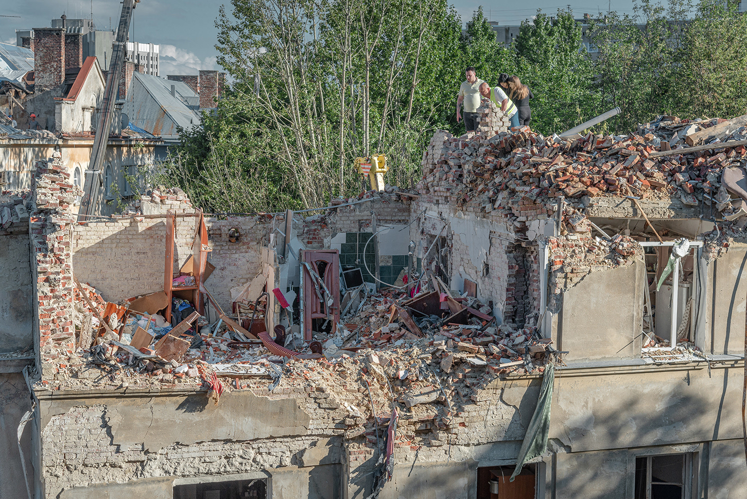 A grieving family surveys the wreckage of their apartment with a demolition service worker after a direct hit by a Russian missile on their apartment in Lviv on July 6. As a result of the missile strike, 10 people were killed and 42 others, including 3 children, were injured. This is the deadliest blow to the civilian population of the city.
