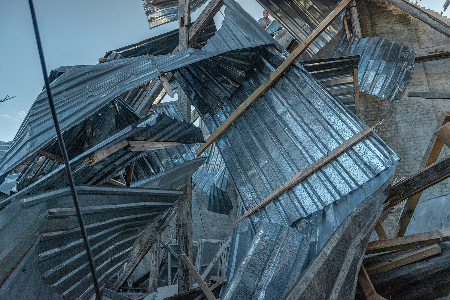 A resident dismantles the roof of a Lviv block of flats destroyed by an explosive wave after being hit by a Russian missile.