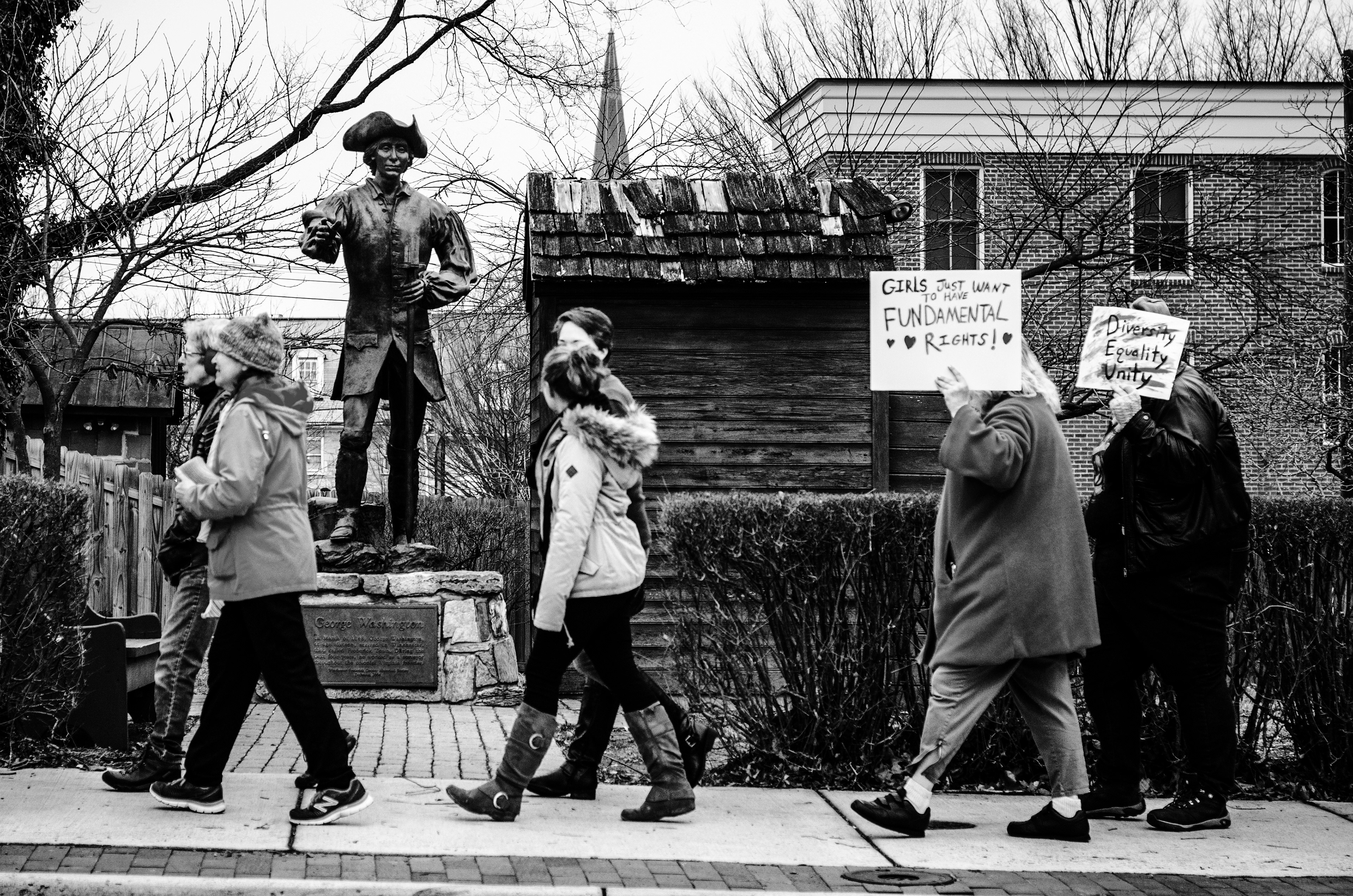 Demonstrators participating in the Winchester Women’s March pass a statue of George Washington on Cork Street beside the building he used as a surveying office from 1755 to 1756. // JANUARY 21, 2017, WINCHESTER, VA