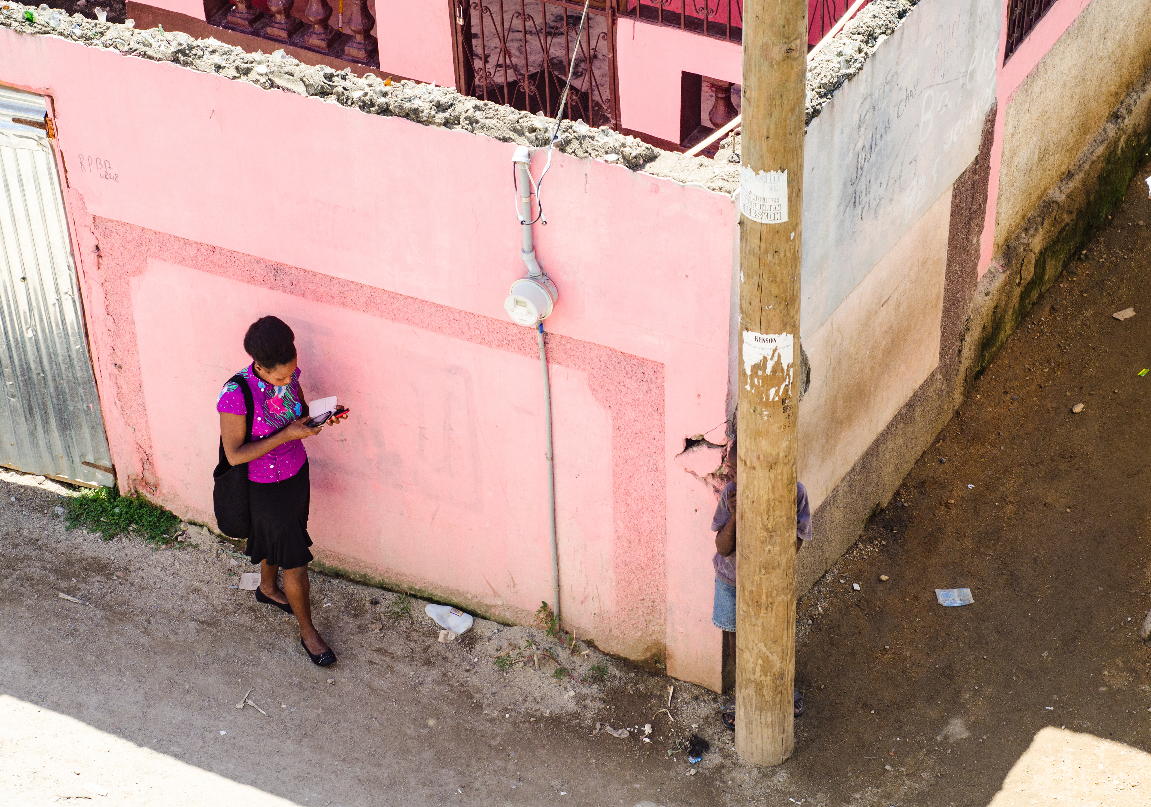 A woman checks her phone on a street corner in Trou-du-Nord, Haiti.