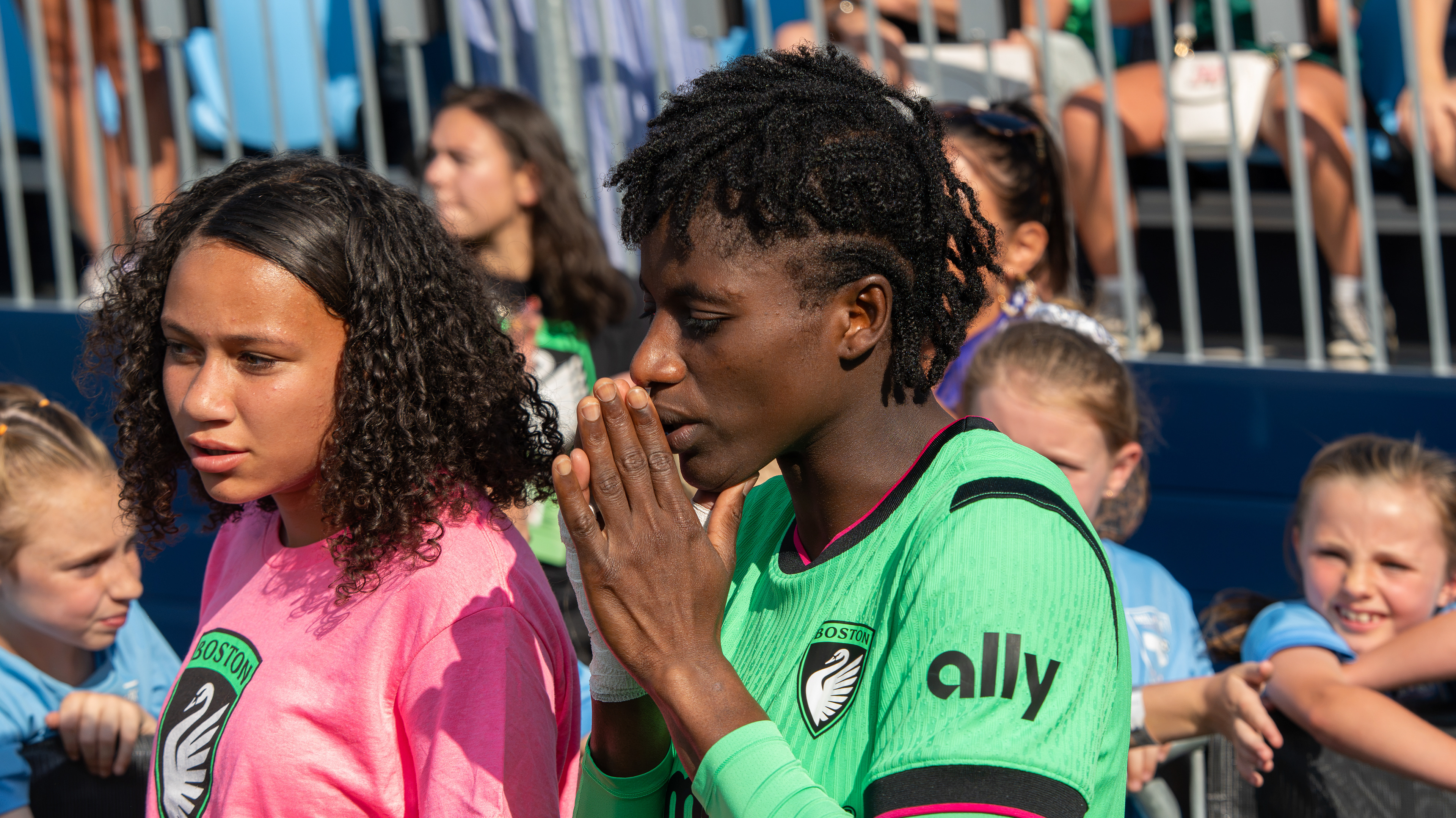 Aïssata Traoré walks out of the Centreville stadium tunnel with teammates beside a Boston Legacy young supporters.