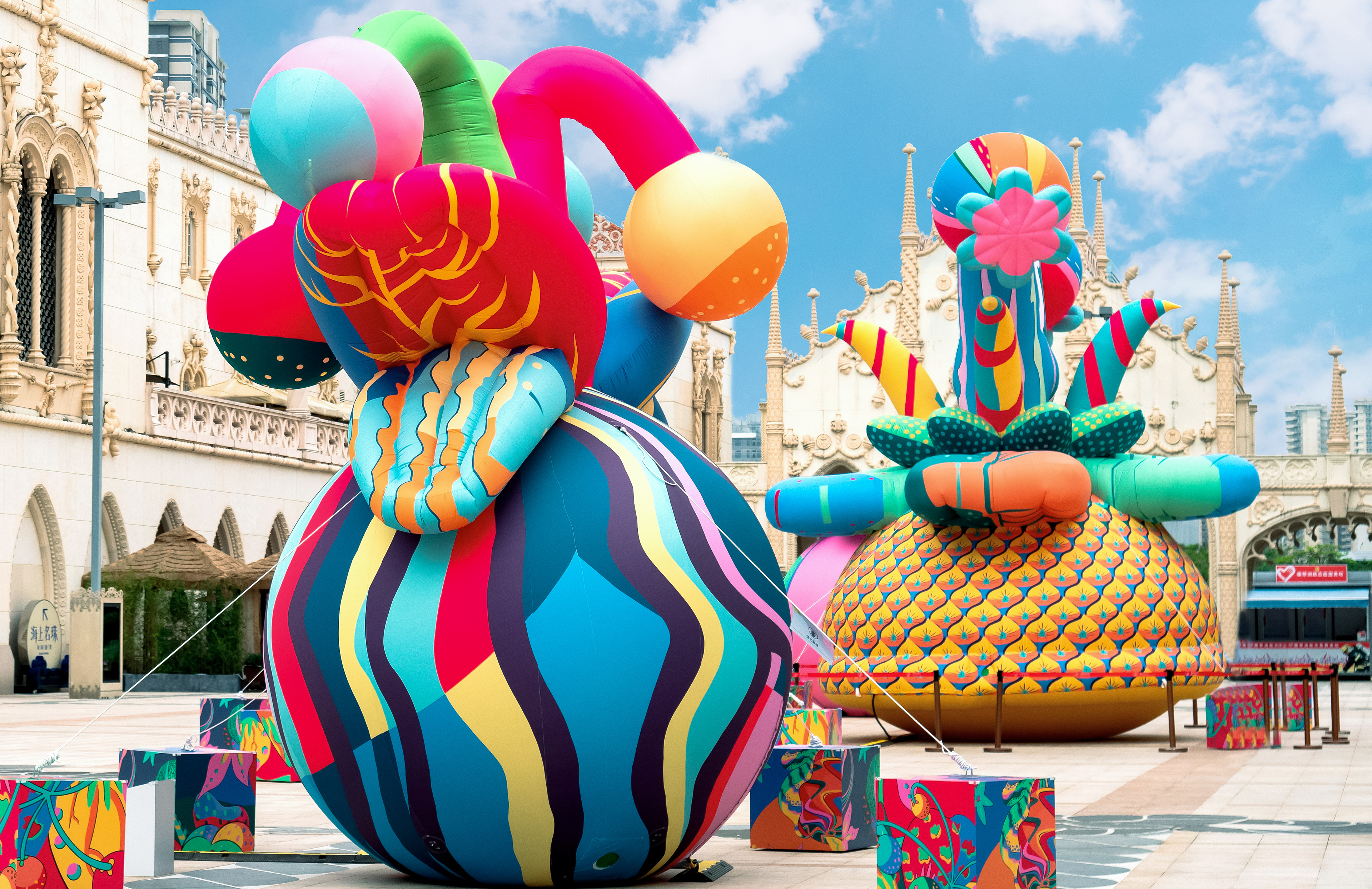 A couple of giant fruit and flower sculptures in a courtyard designed by Sam Wilde as part of a public art exhibition in China.