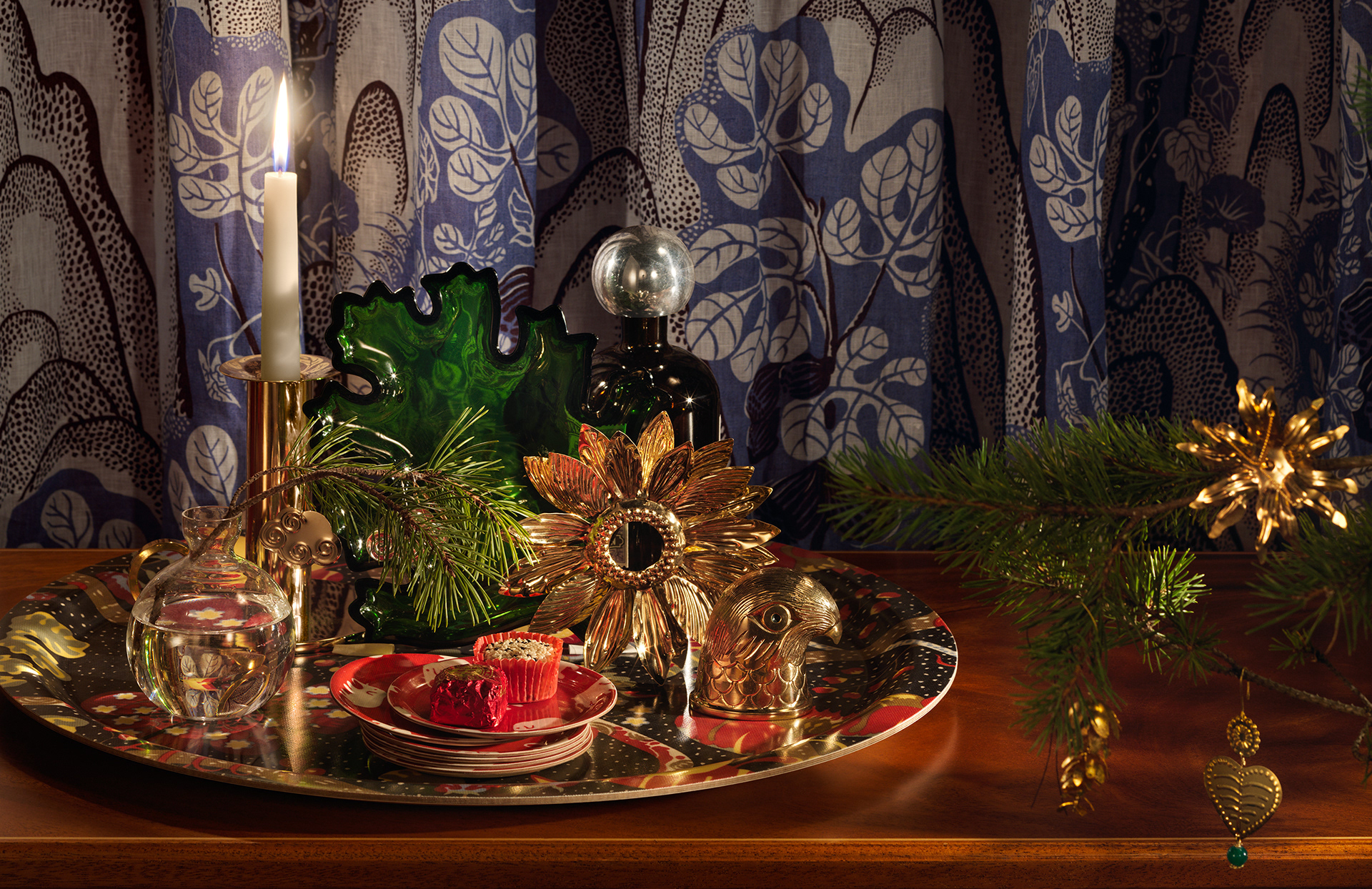 Brass sunflower candle ring designed by Sam Wilde sitting amongst ornaments on a Svenskt Tenn tray.