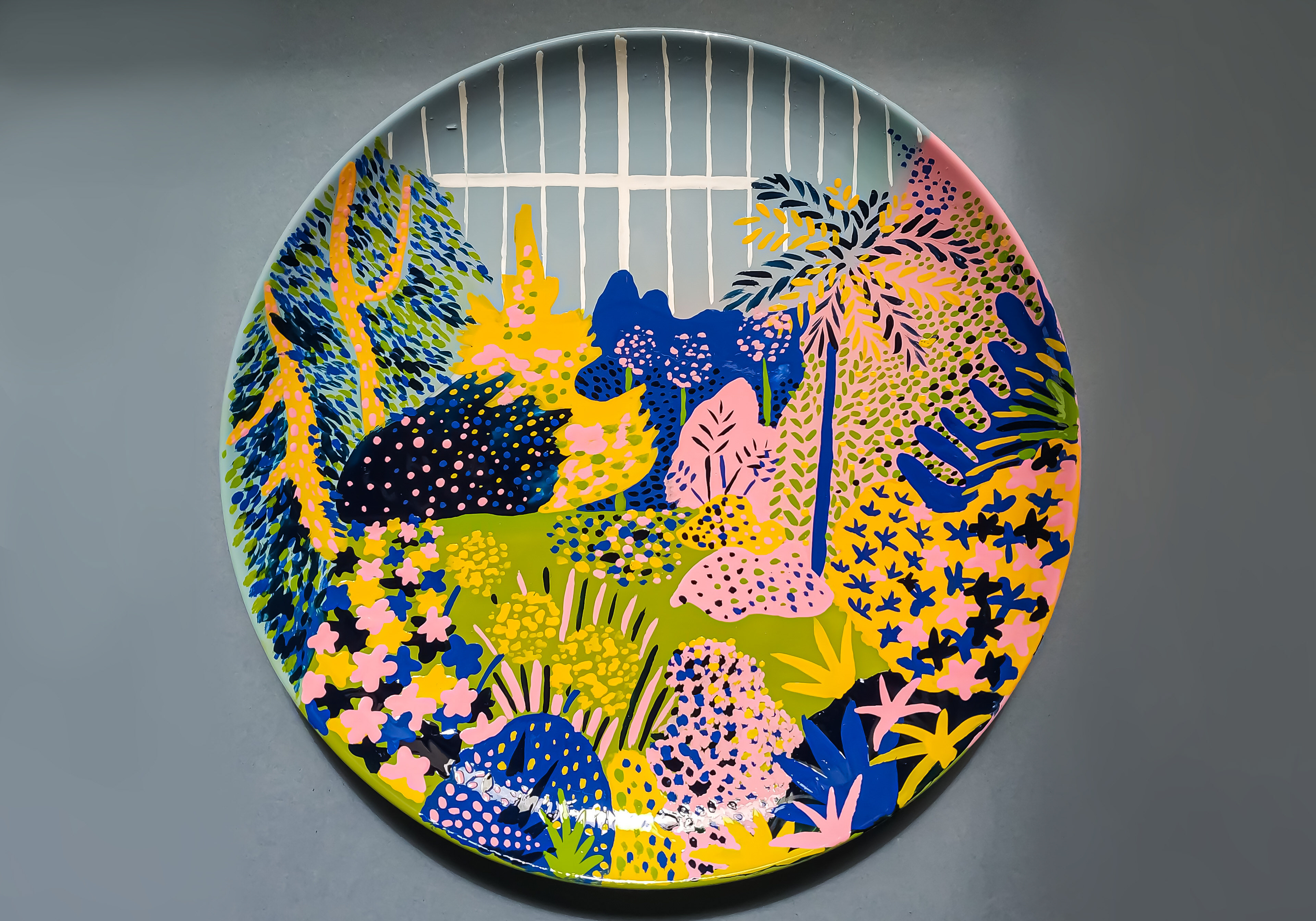 A small hand-painted ceramic plate depicting an overgrown greenhouse filled with plants.