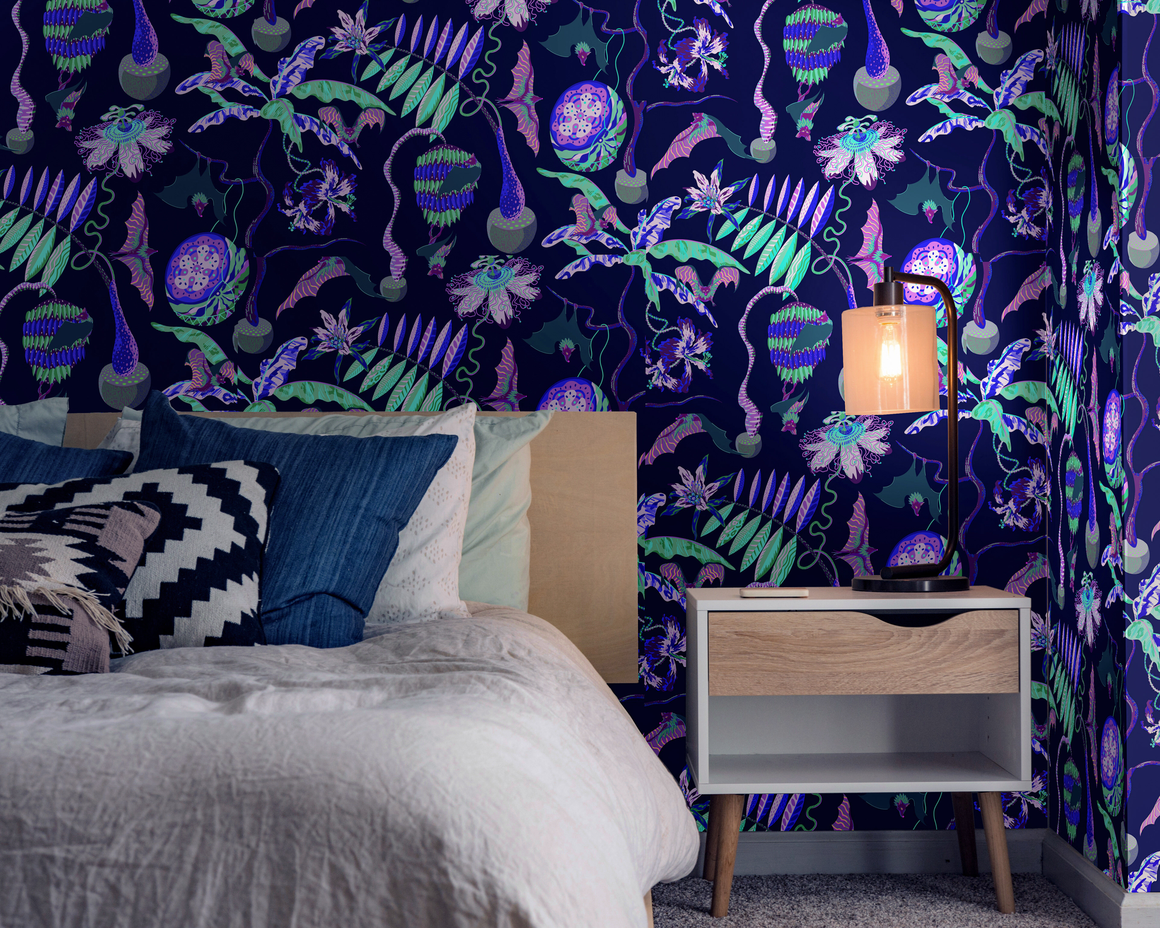 Cosy bedroom showing illustrative dark patterned wallpaper of bats in a neon jungle world.
