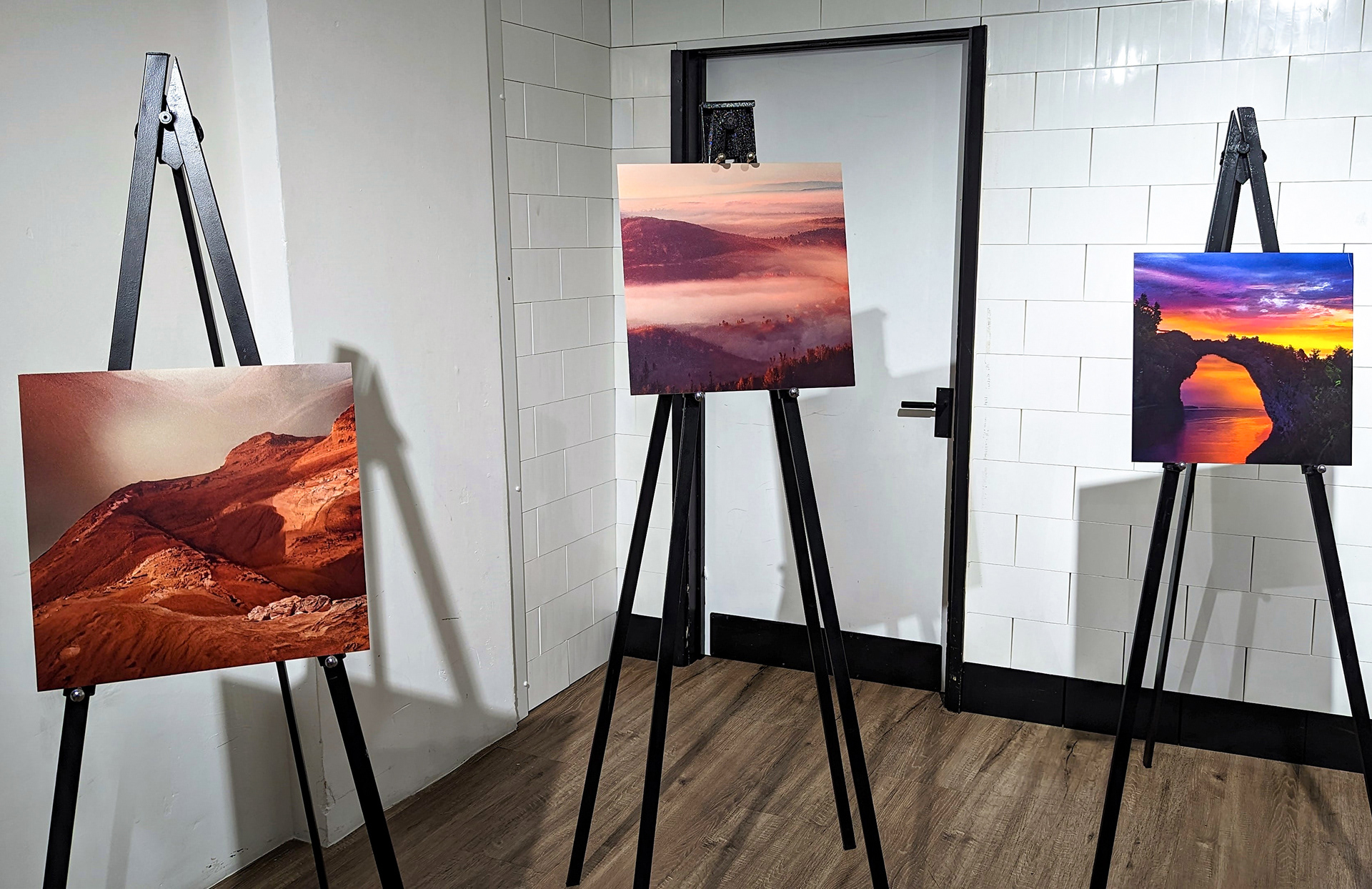 Three canvases depicting AI art standing on black easels.