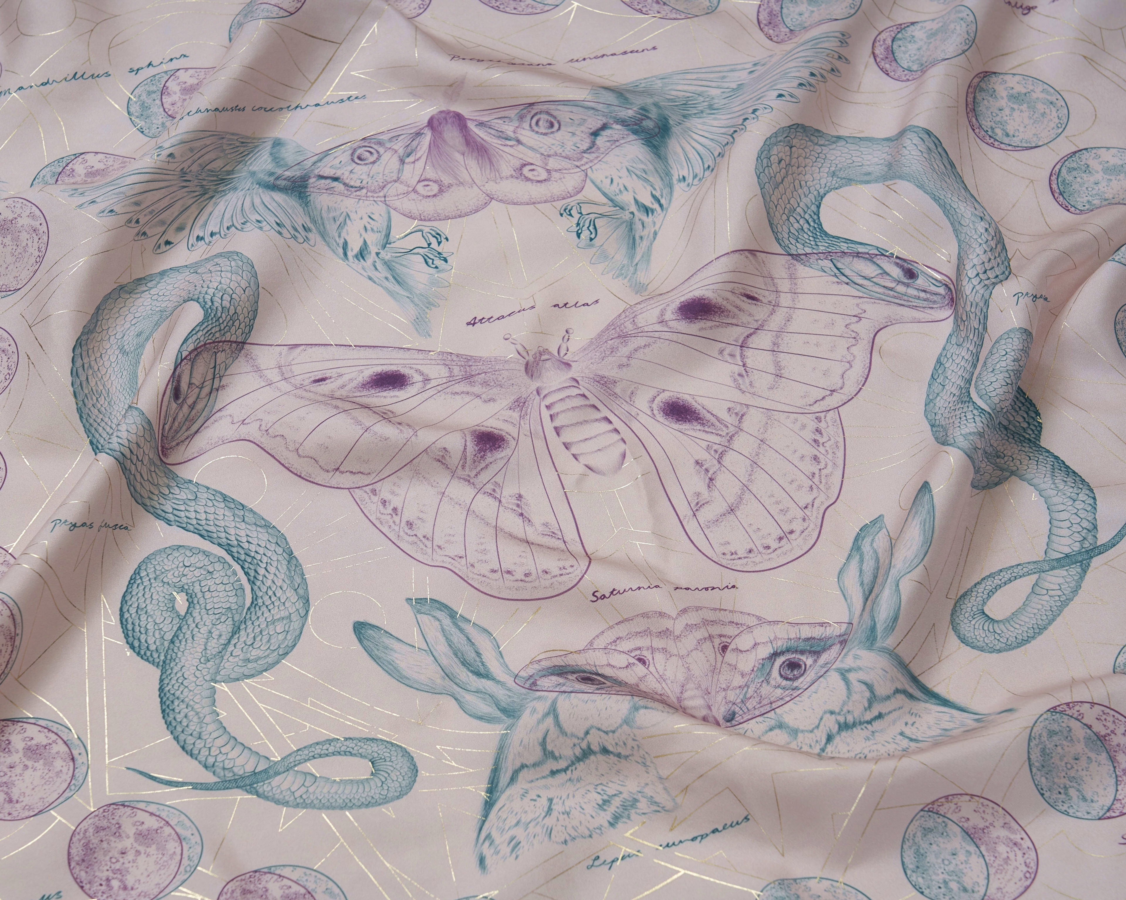 An exquisite silk scarf with gold detailing showing a giant atlas moth next to two snakes.