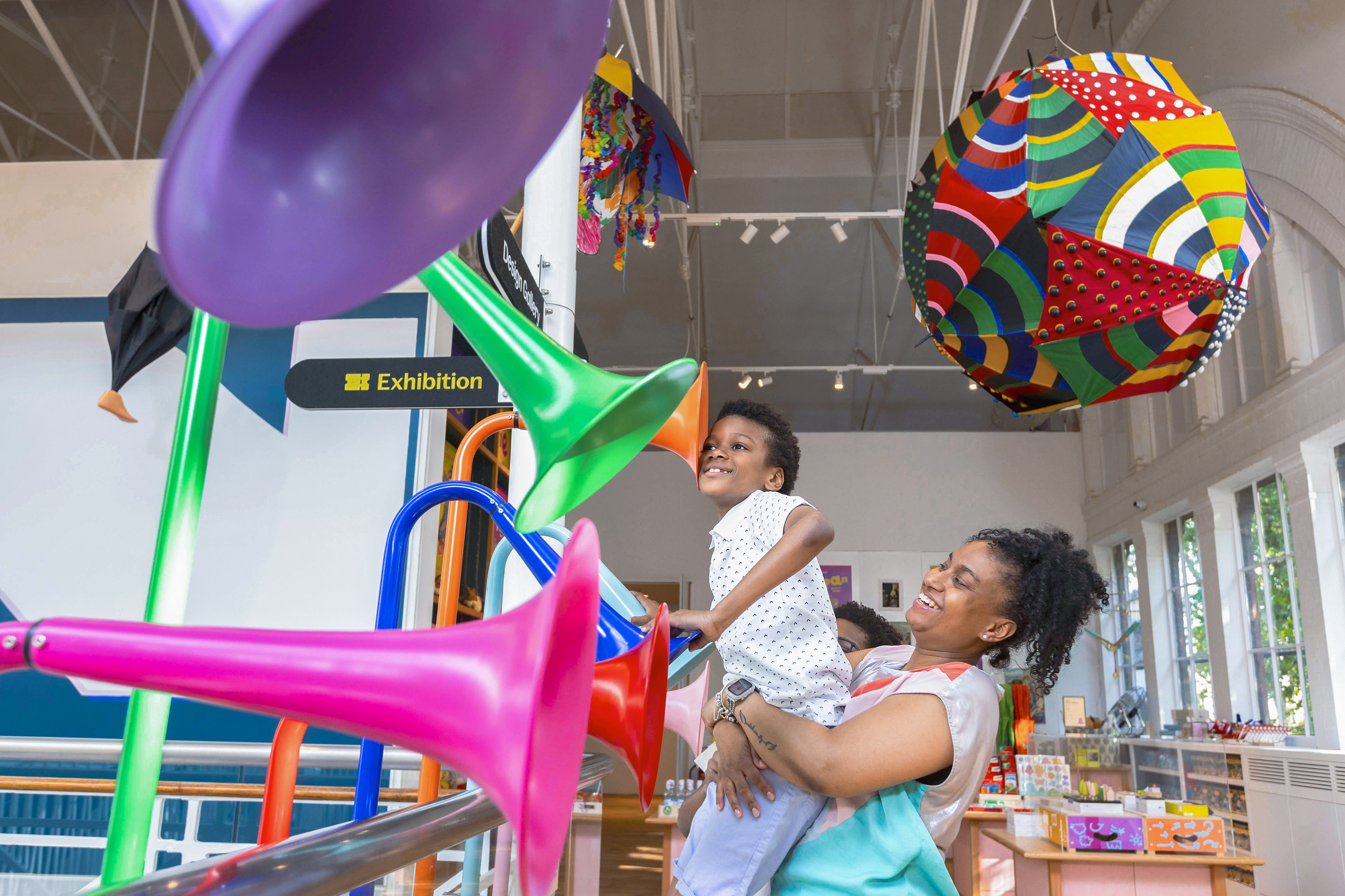 A playful image of a mother and son enjoying a art installation featuring a umbrella sculpture.