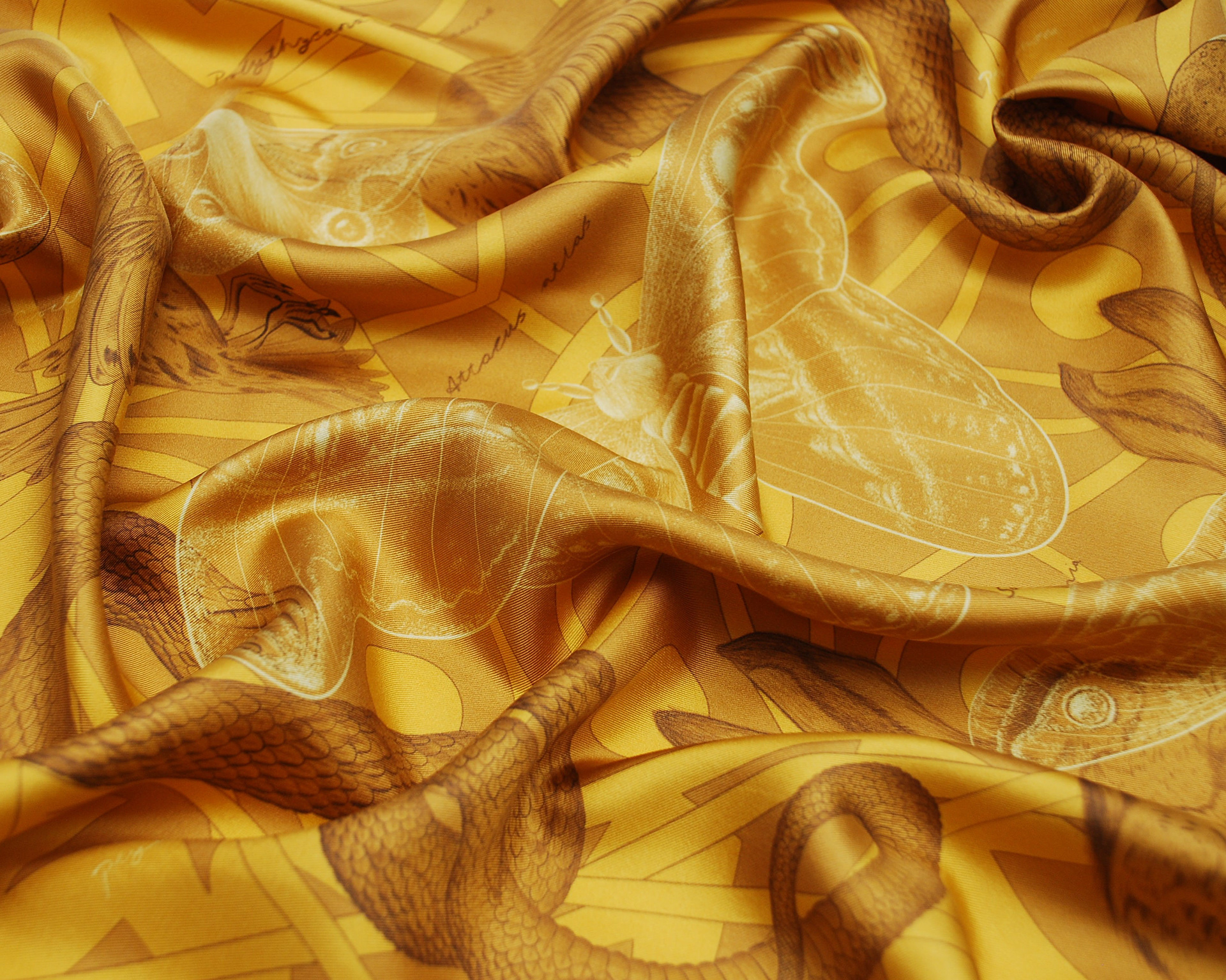 A luxurious gold silk scarf showing an illustrated moth and fine art detailing.