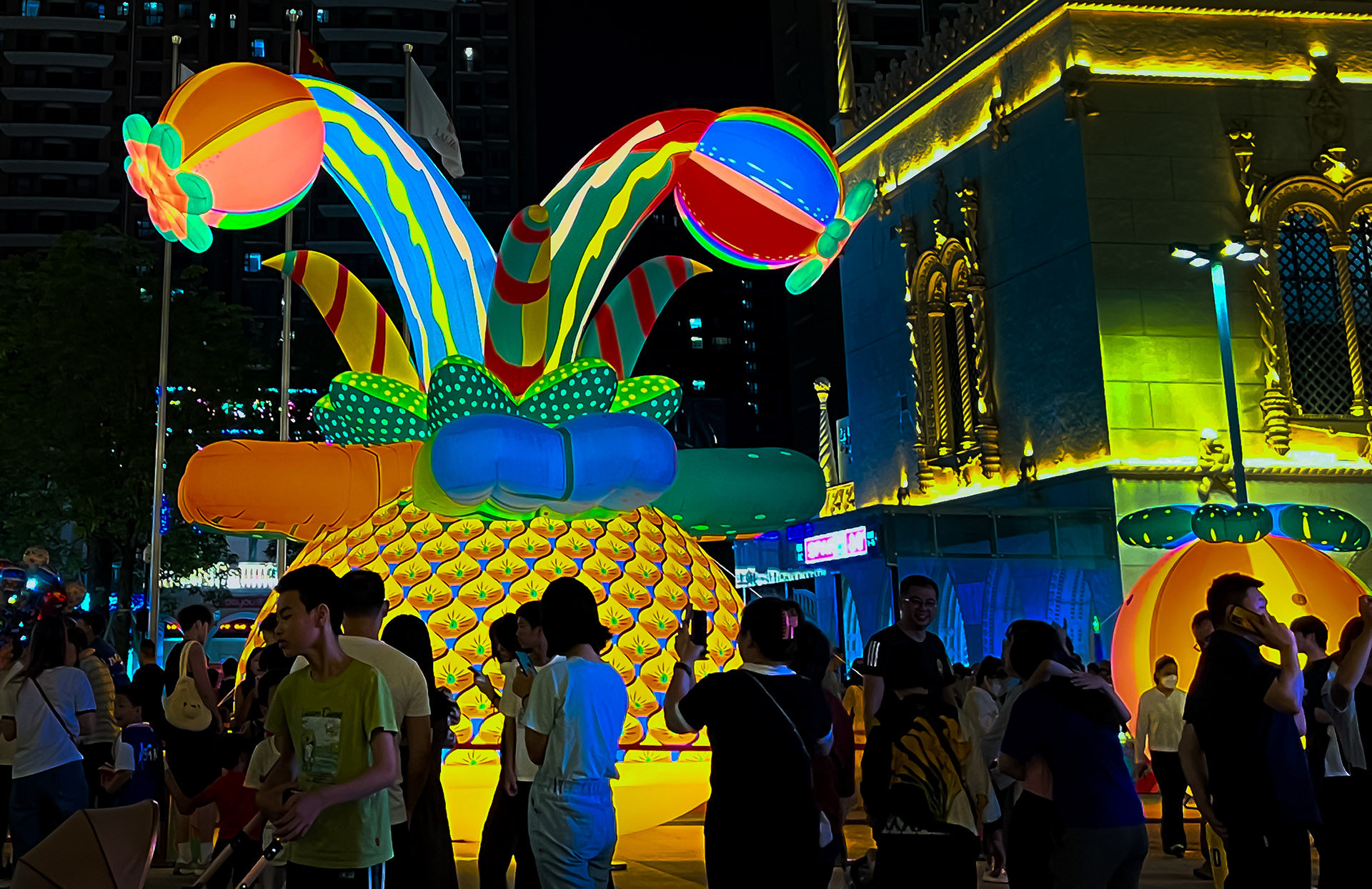A huge glowing pineapple sculpture designed by Sam Wilde against a lively urban backdrop.