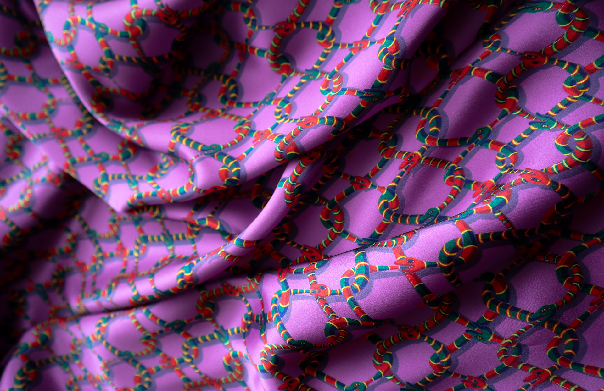 Draped purple fabric with a pattern depicting a chain-link fence made entirely of snakes.