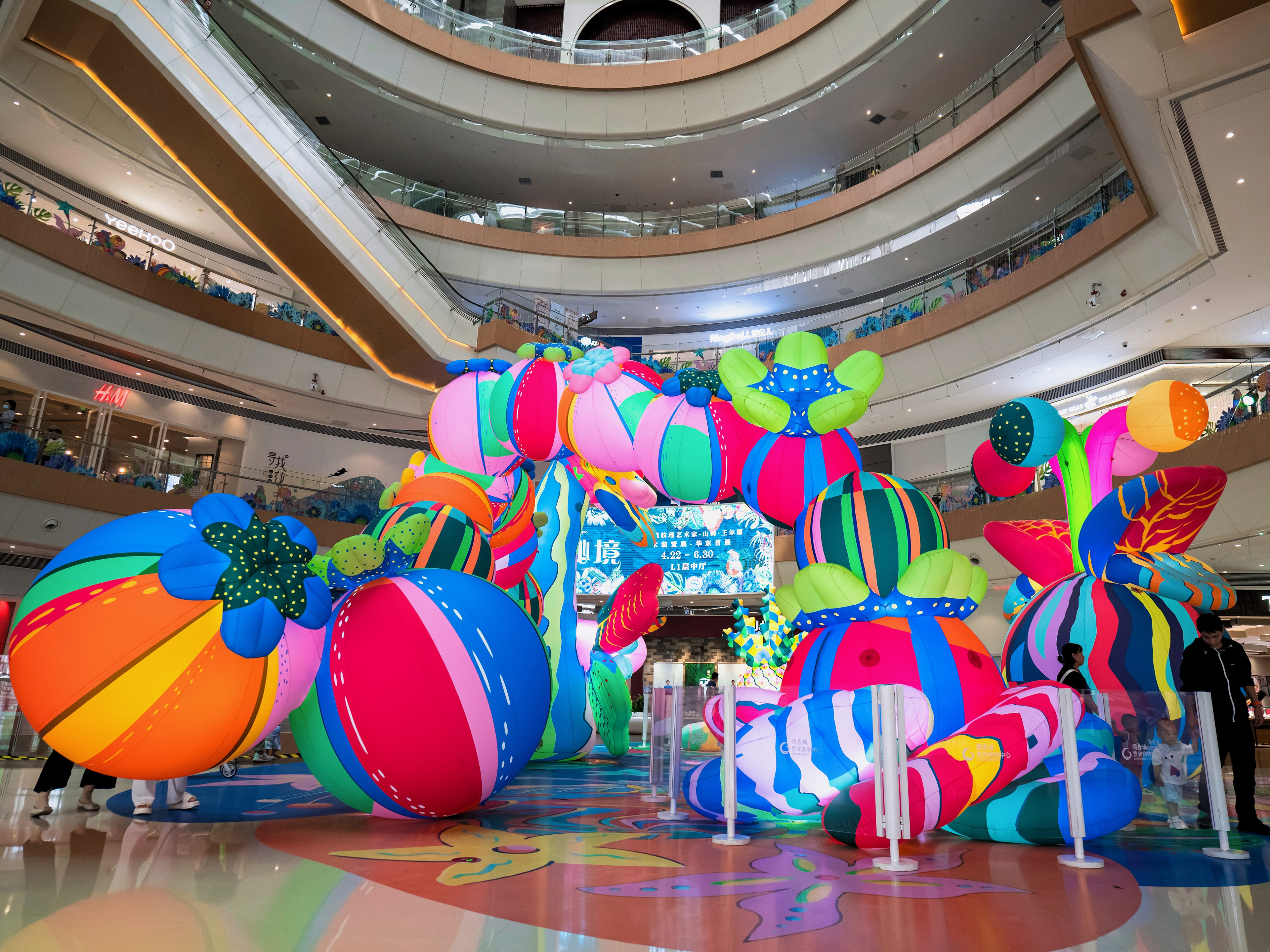 A glowing inflatable archway sculpture comprised of larger-than-life neon patterned colourful fruits.