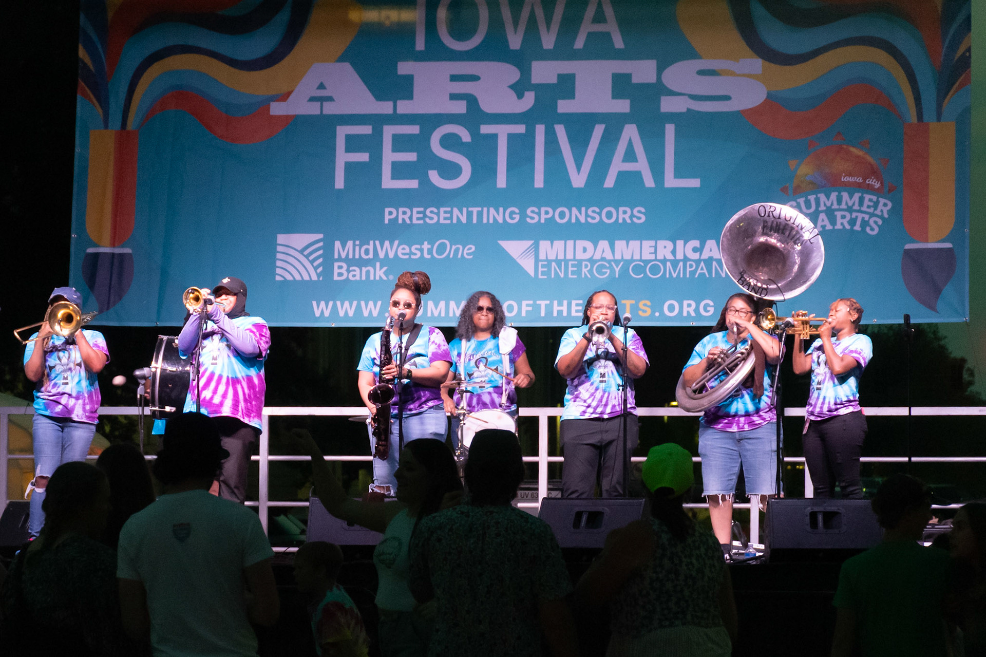 IOWA CITY, IOWA – JUNE 6, 2025: The Original Pinettes Brass Band performs under the Iowa Arts Festival banner with full brass power and unified precision. Their vibrant sound and sisterhood of talent made for an unforgettable festival finale.