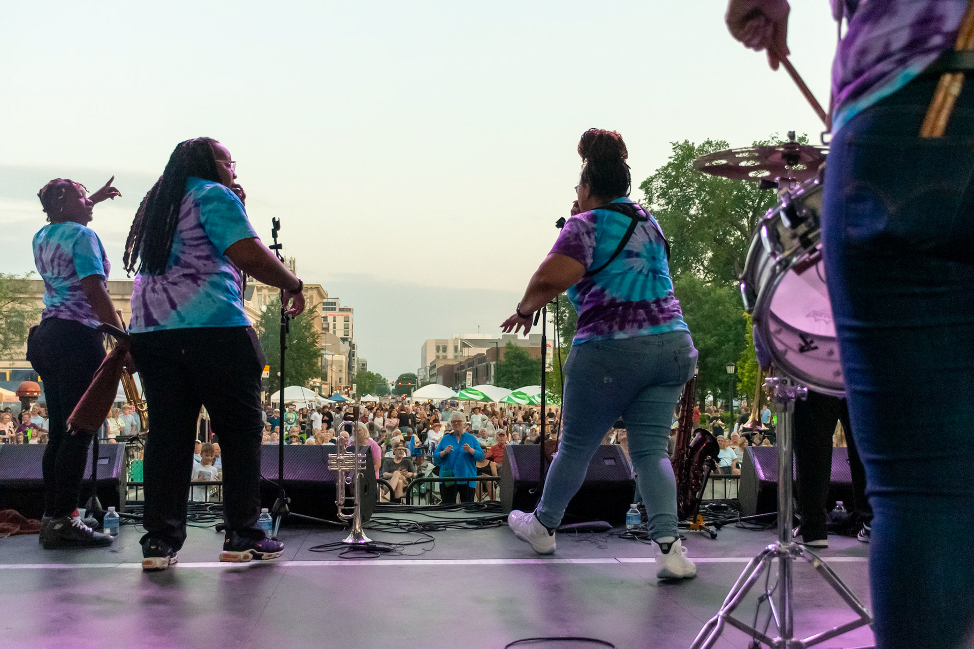 IOWA CITY, IOWA – JUNE 6, 2025: The Original Pinettes Brass Band energizes a packed Clinton Street as seen from the stage during the Iowa Arts Festival. With the sunset at their backs and a sea of fans ahead, the band lit up the city with brass, soul, and celebration.