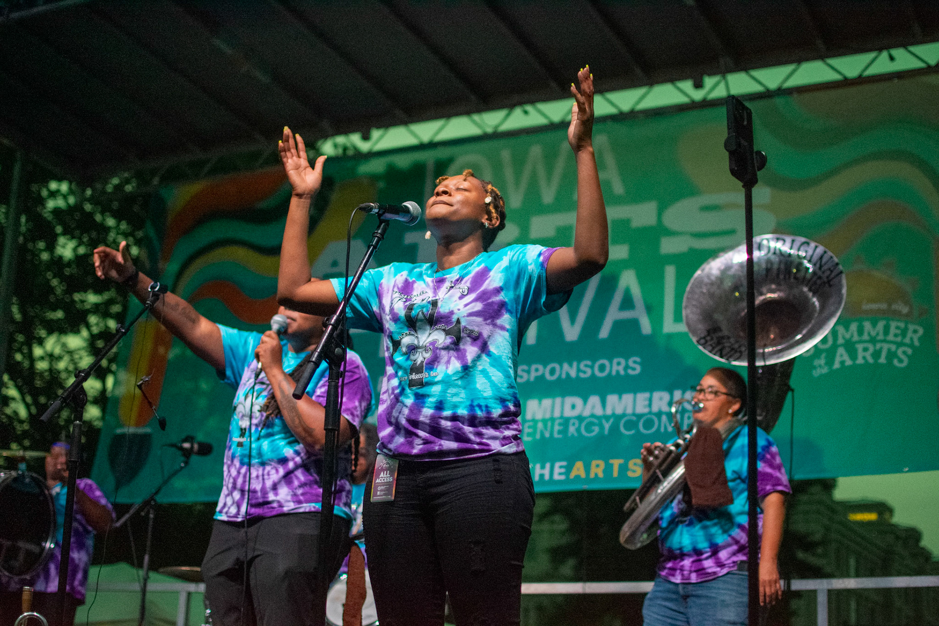 IOWA CITY, IOWA – JUNE 6, 2025: Jazz Henry, trumpet player and vocalist for The Original Pinettes Brass Band, raises her hands as the group electrifies the crowd at the Iowa Arts Festival. The all-female brass band delivered a powerful performance, blending classic New Orleans brass with their own unique flair.