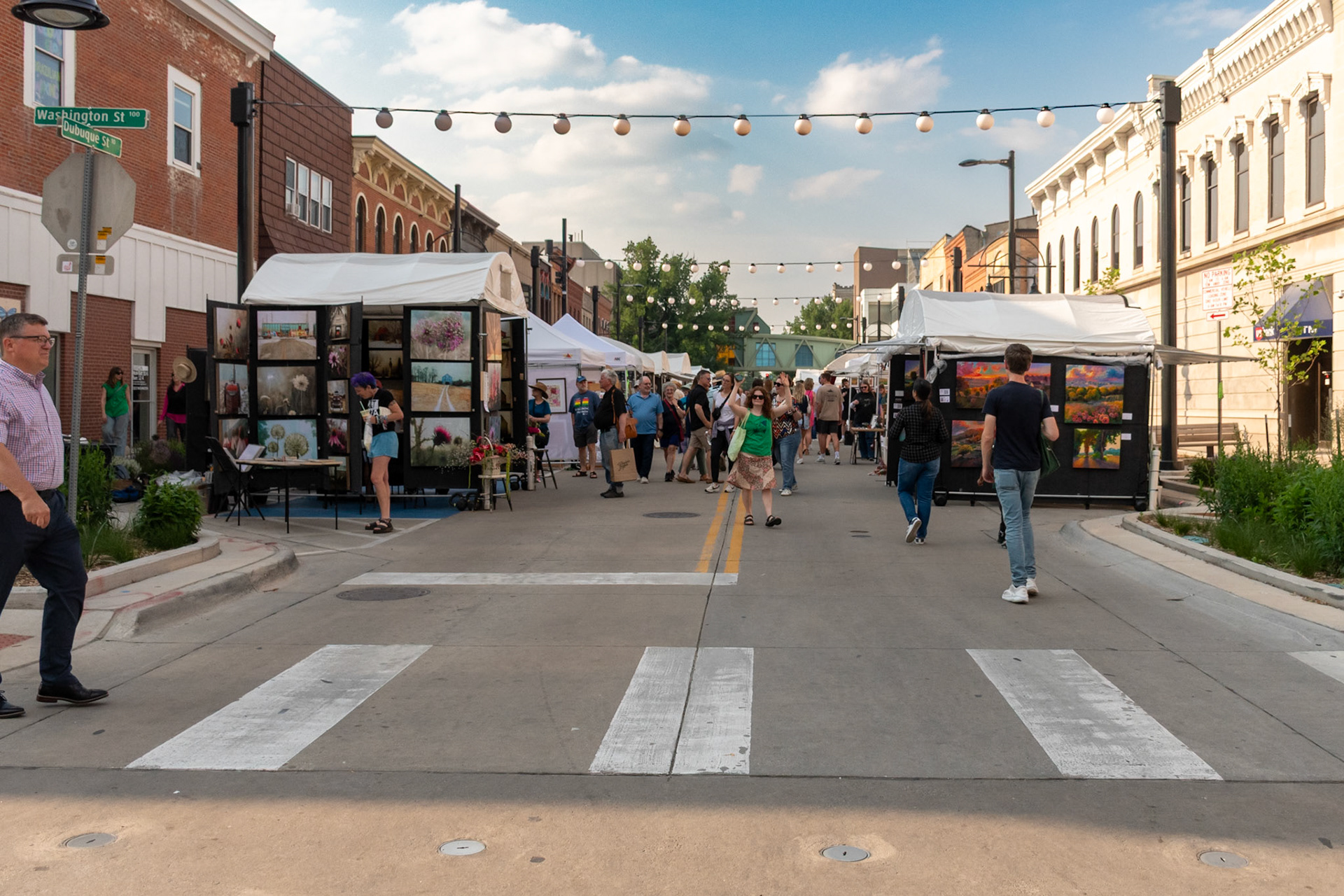 IOWA CITY, IOWA/UNITED STATES – JUNE 6, 2025: Festivalgoers explore art booths along North Dubuque Street during the Iowa Arts Festival under bright summer skies.