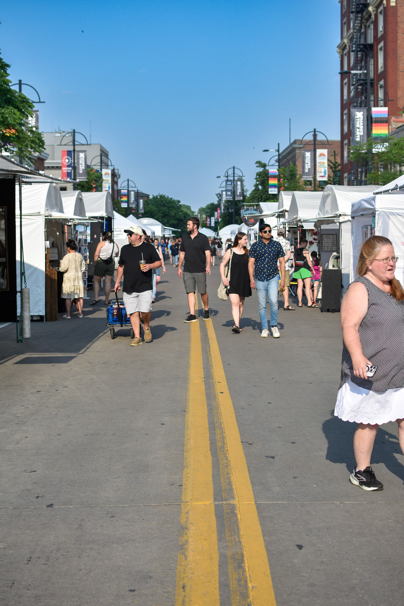 IOWA CITY, IOWA/UNITED STATES – JUNE 6, 2025: Visitors stroll East Washington Street during the Iowa Arts Festival, browsing art vendor booths and enjoying the summer weather.