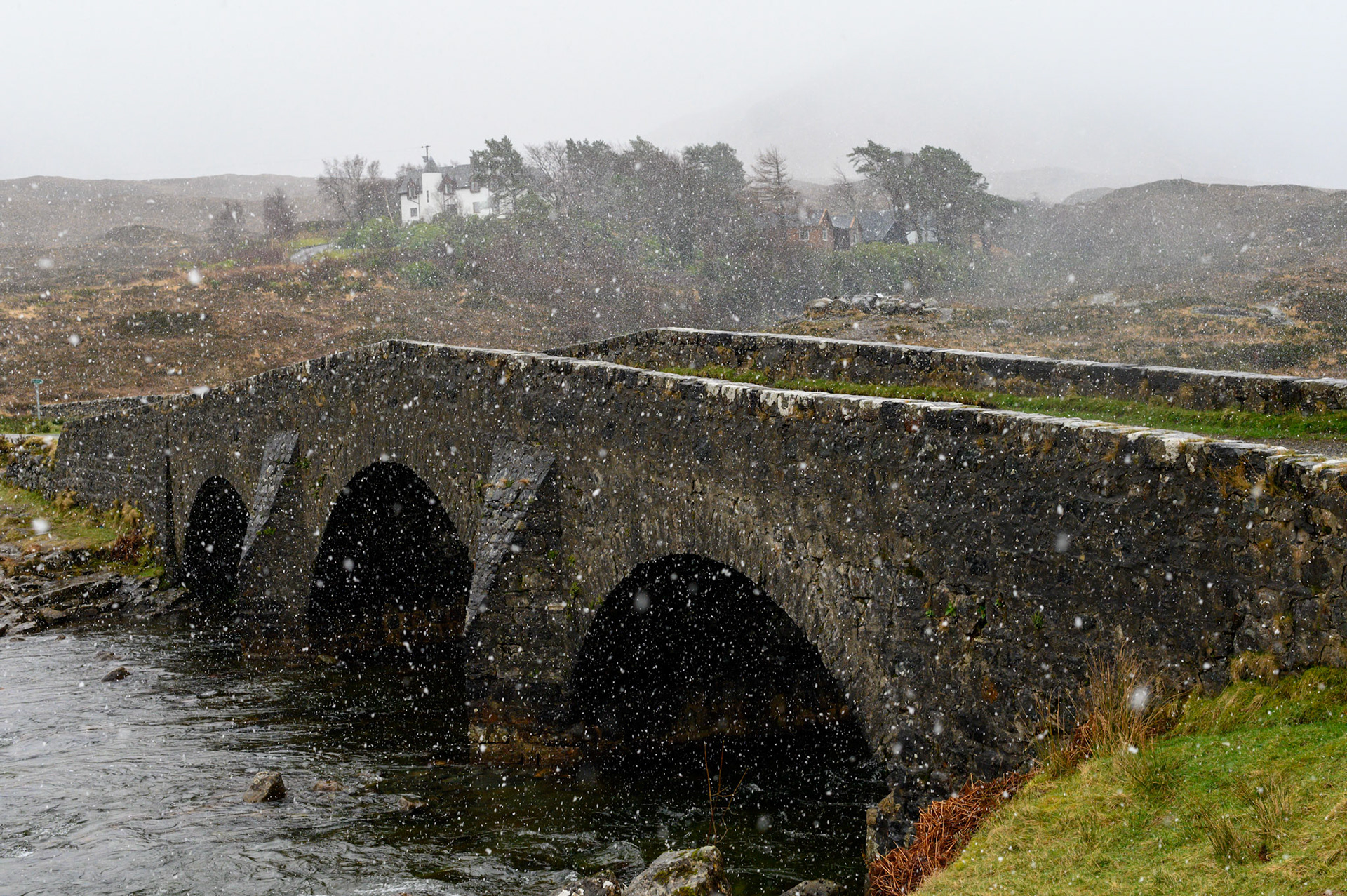 Big wet snow flakes curtain the old bridge at Sligachan on Skye. The Black Culins are in the background.