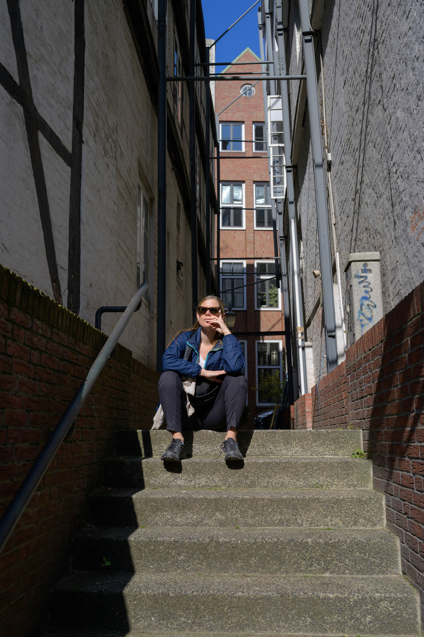 Sheryl sitting on steps by a Hamburg canal, pondering the options for breakfast once shops open. It was a holiday of some sort. We often get that when arriving in a city.