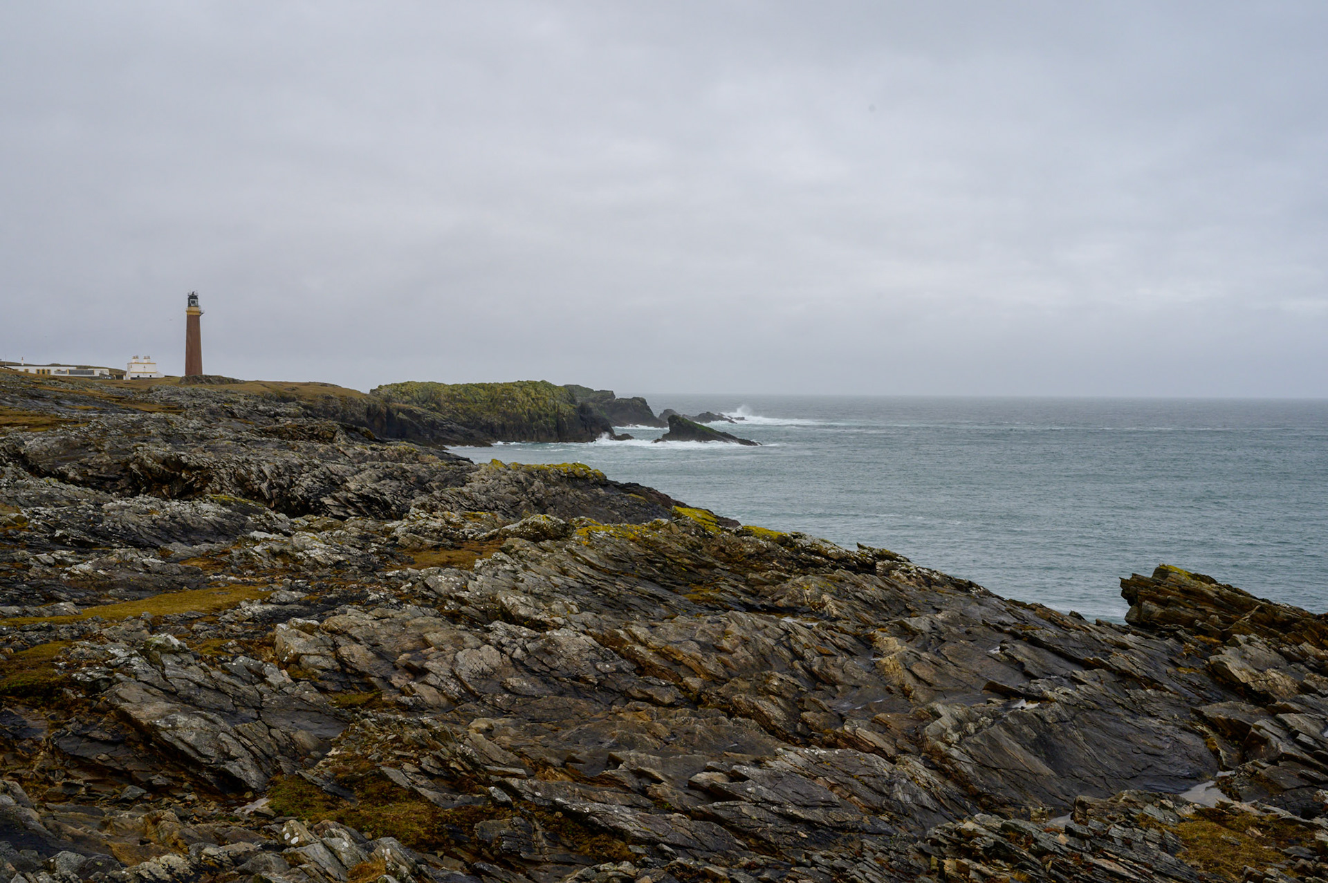 The Ness lighthouse seen across the tops of Lewis cliffs scoured bare by the Atlantic winds