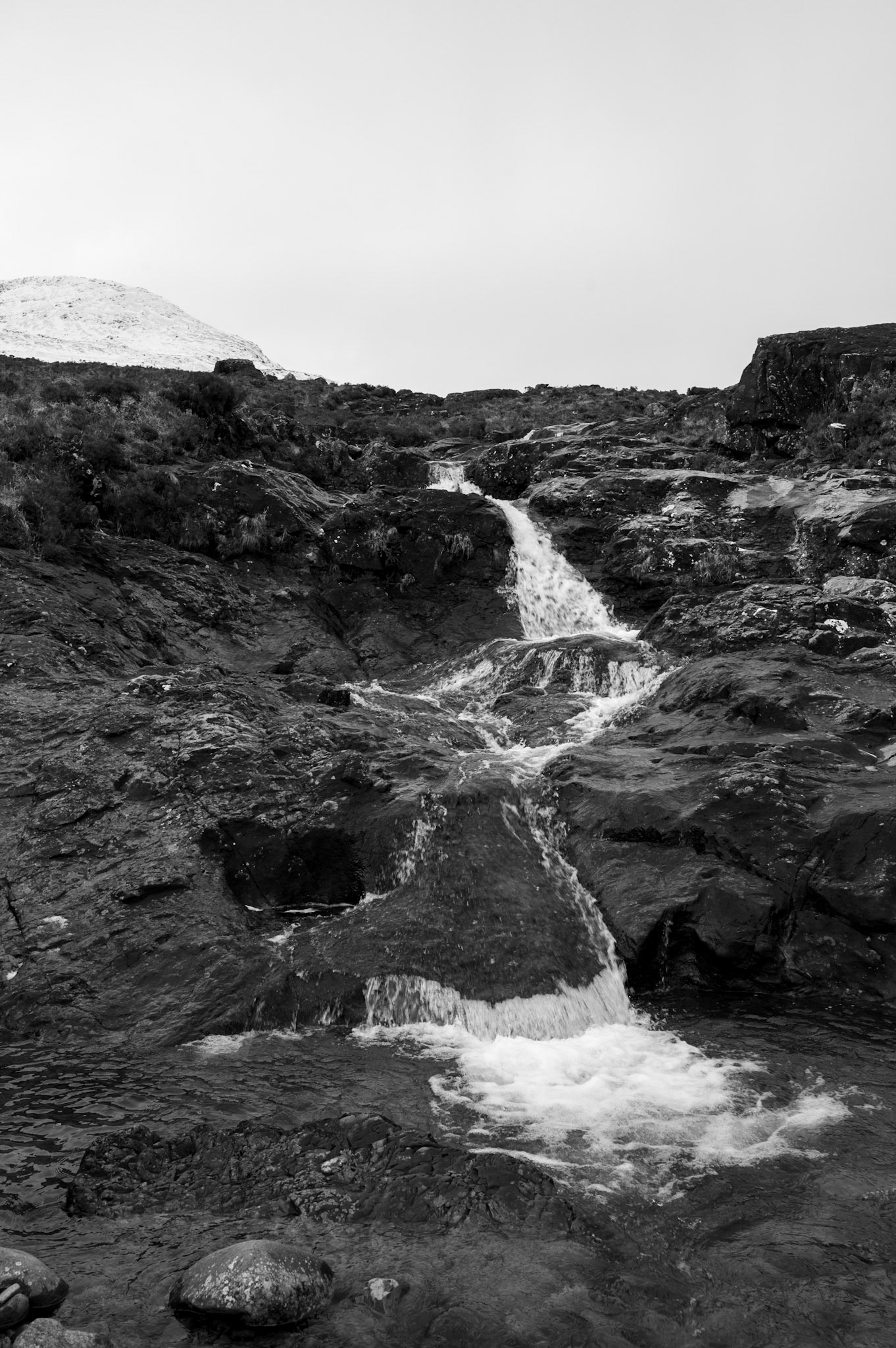 Snowmelt tumbling down black rocks and peat bog.