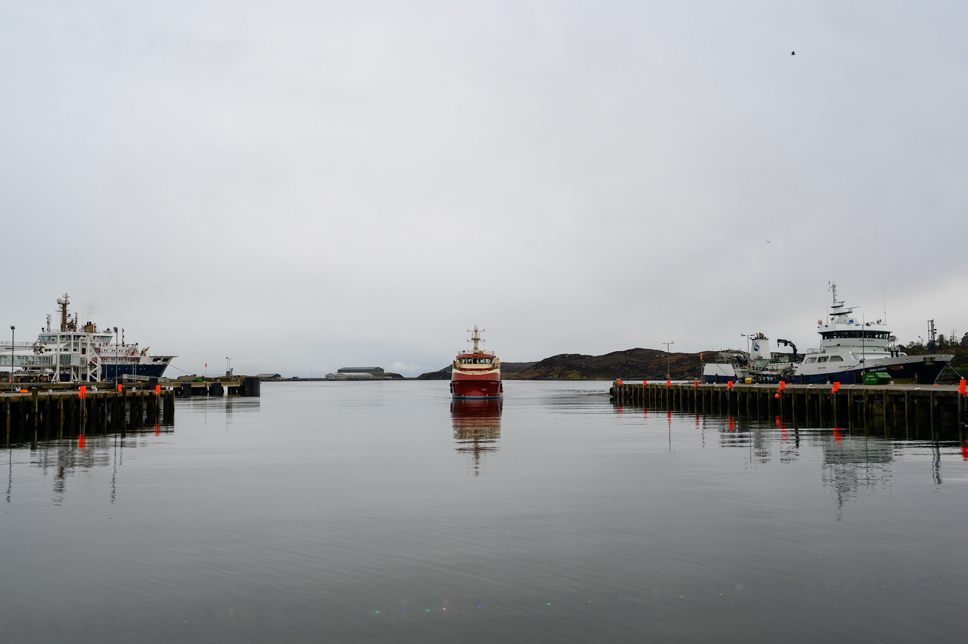A boat enters Stornoway harbour on a still afternoon.
