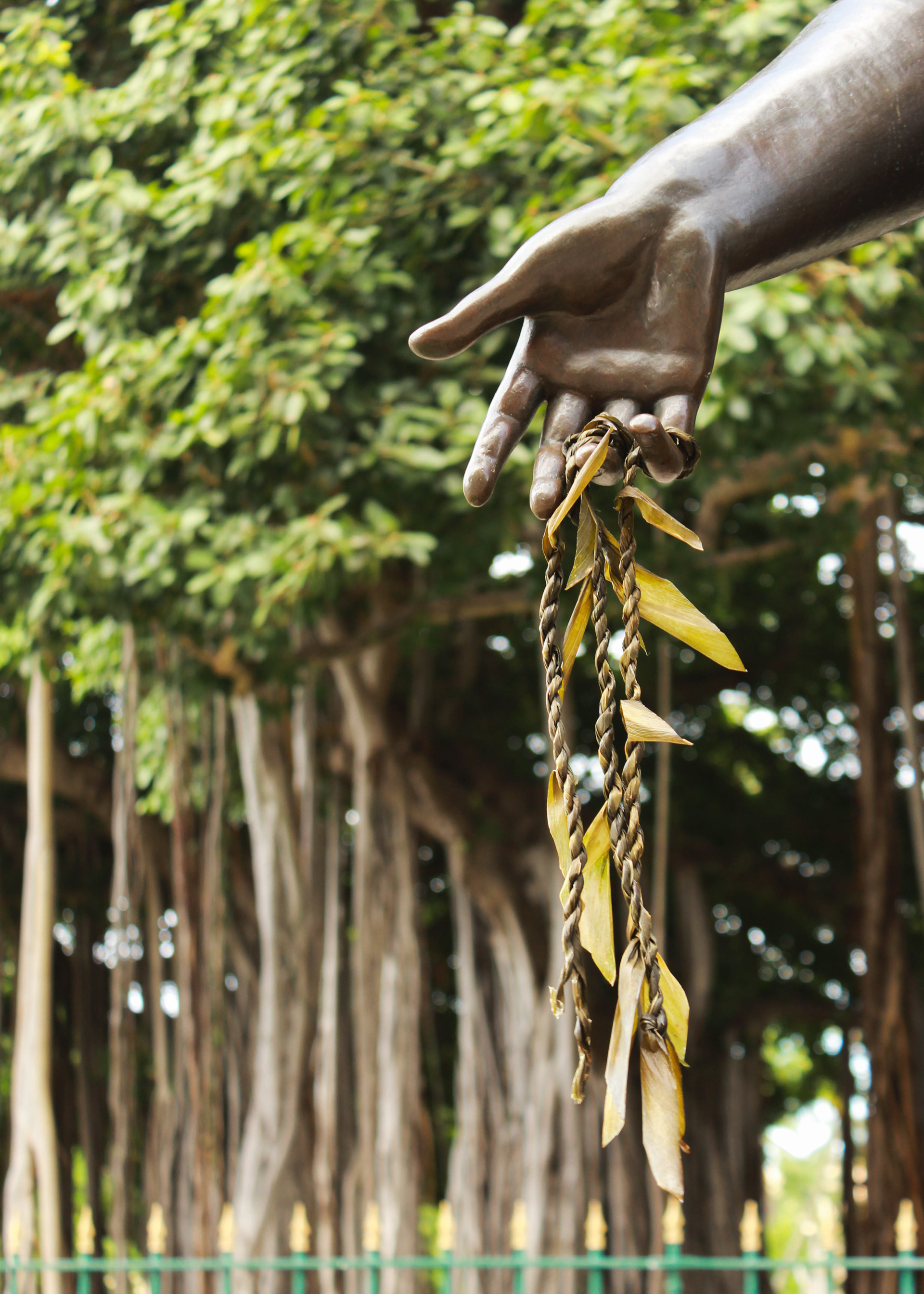 A ti leaf lei hangs from the outstretched hand of the Queen Lili'uokalani statue.