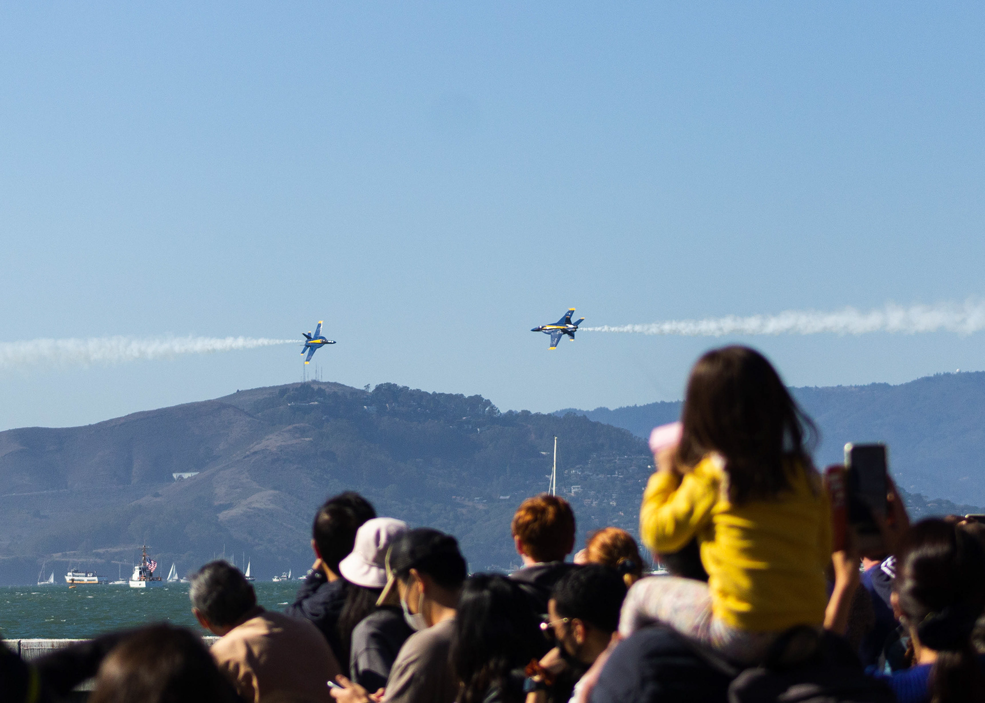 The crowd at Pier 39 watches the Blue Angels fly over San Francisco Bay.
