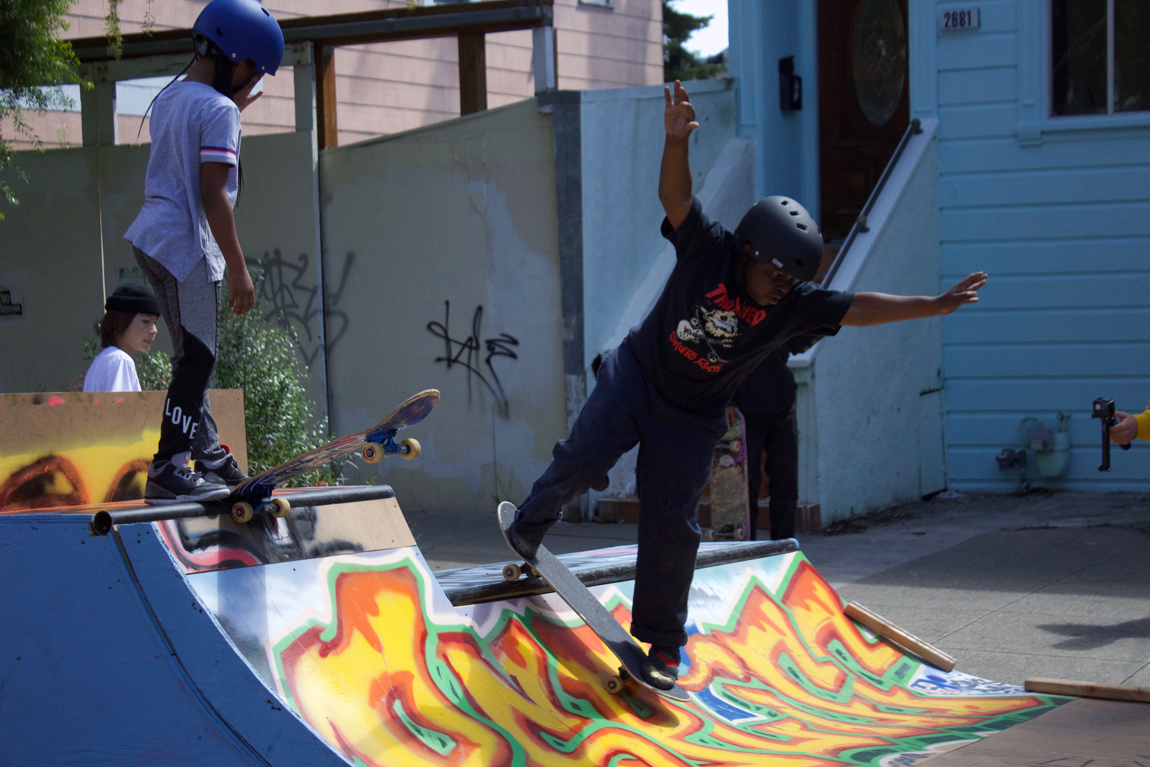 Two boys skateboard at a street fair.