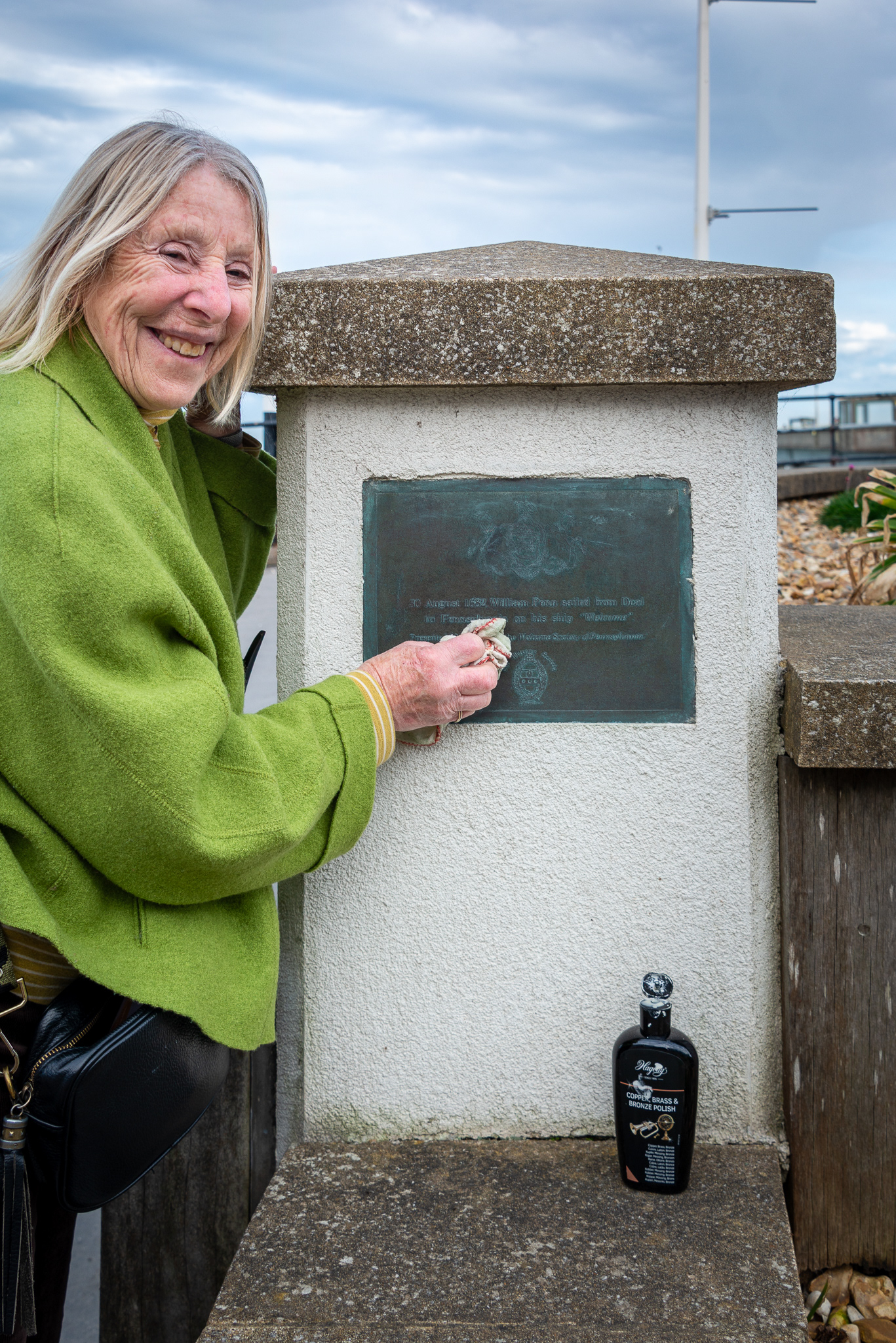 Helga, cleaning the brass plaque on the approach to Deal Pier, 21st March, 2025.  The plaque records the journey made by William Penn, who sailed from Deal on 30th August 1682 to Pennsylvannia in his ship the 'Welcome'. Penn's arrival founded the Province of Pennsylvannia in the British Colonial Era. The plaque was presented by the Welcome Society of Pennsylvannia on 6th May 1982.