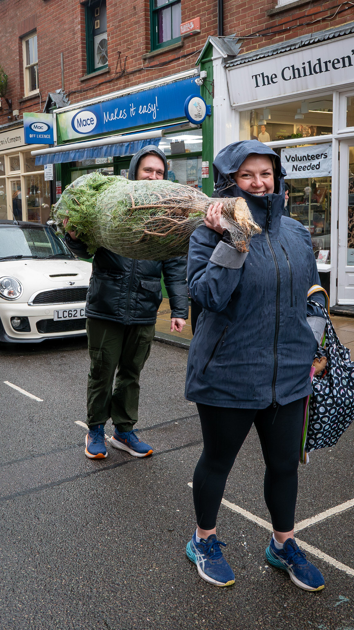 Isobel and Mat carrying their Christmas tree home down the High Street, 22nd November, 2025. Isobel works for the charity Comic Relief. Mat is a banker. www.denizensofdeal.com