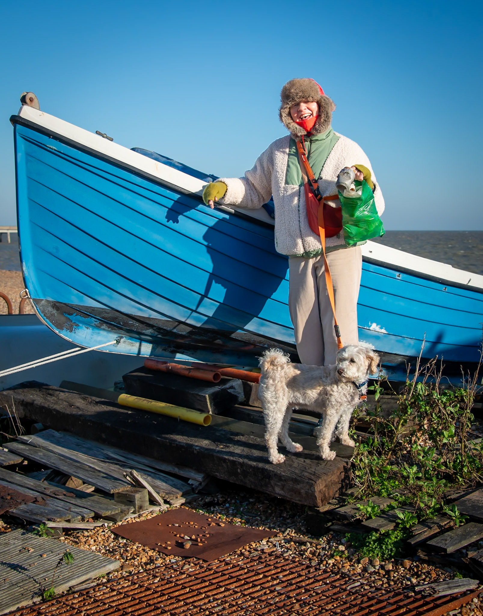 Maggie, a book keeper, part time waitress and litter picker and her dog, Dora, a Schnoodle. A very sunny but cold day on Deal beach, 9th January, 2024.