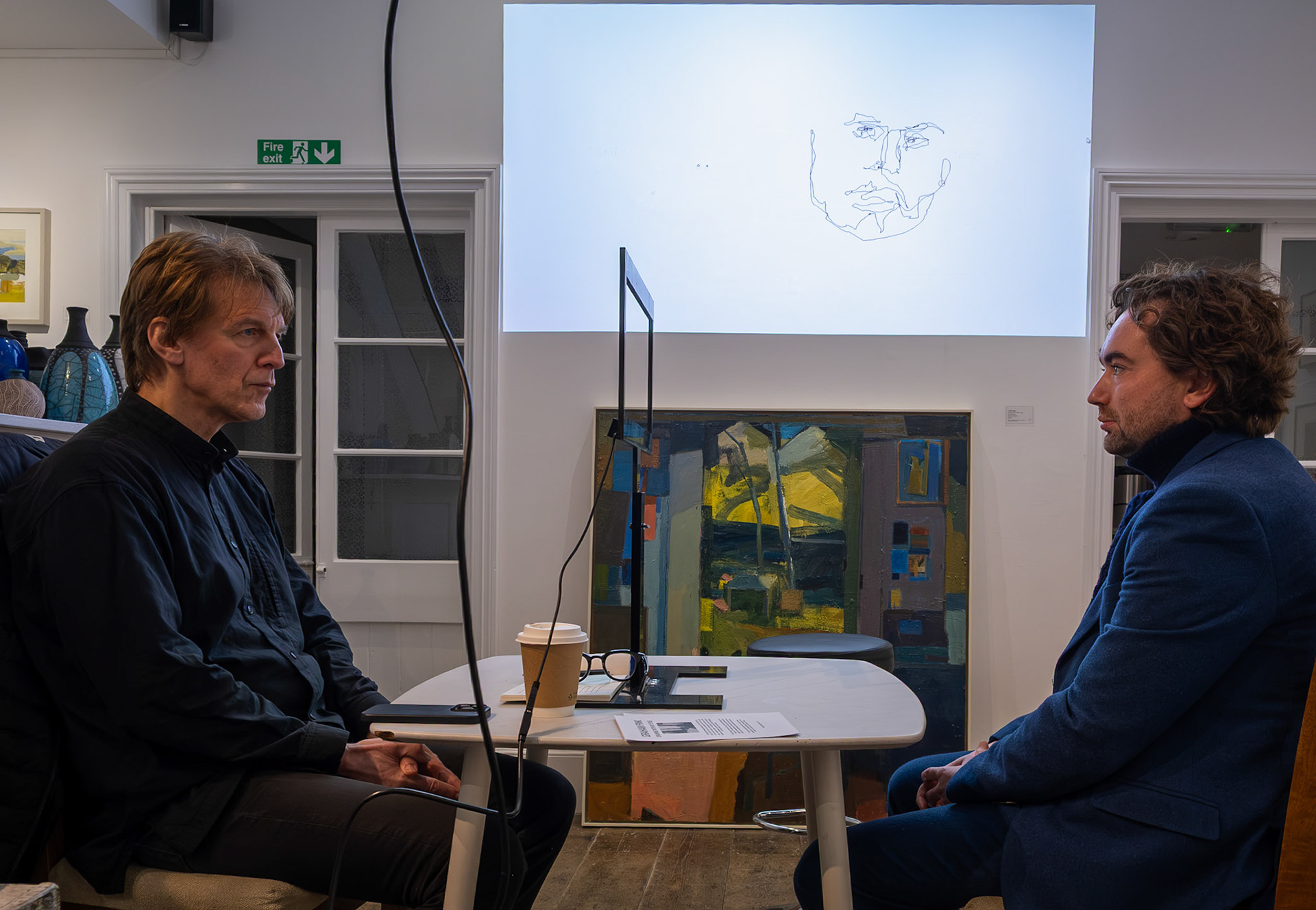 Artist Graham Fink producing an 'eye drawing' of Miles Corley at the Linden Hall Studio, 22nd November, 2025. Graham draws by keeping his head extremely still and guiding his eyes around the features of the subject while the sketch is captured by a computer and projected, as it emerges, onto a big screen.  https://www.lindenhallstudio.com/