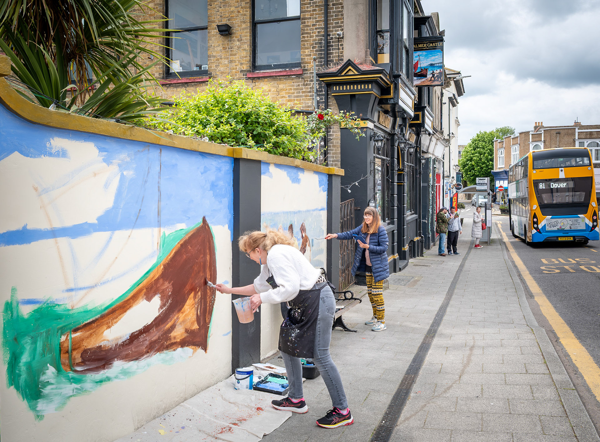 Stephanie Fuller and Penny Bearman painting a new mural on the wall around the beer and music  garden of the Walmer Castle PH, South Street, Deal, as part of Deal Art Streets. 