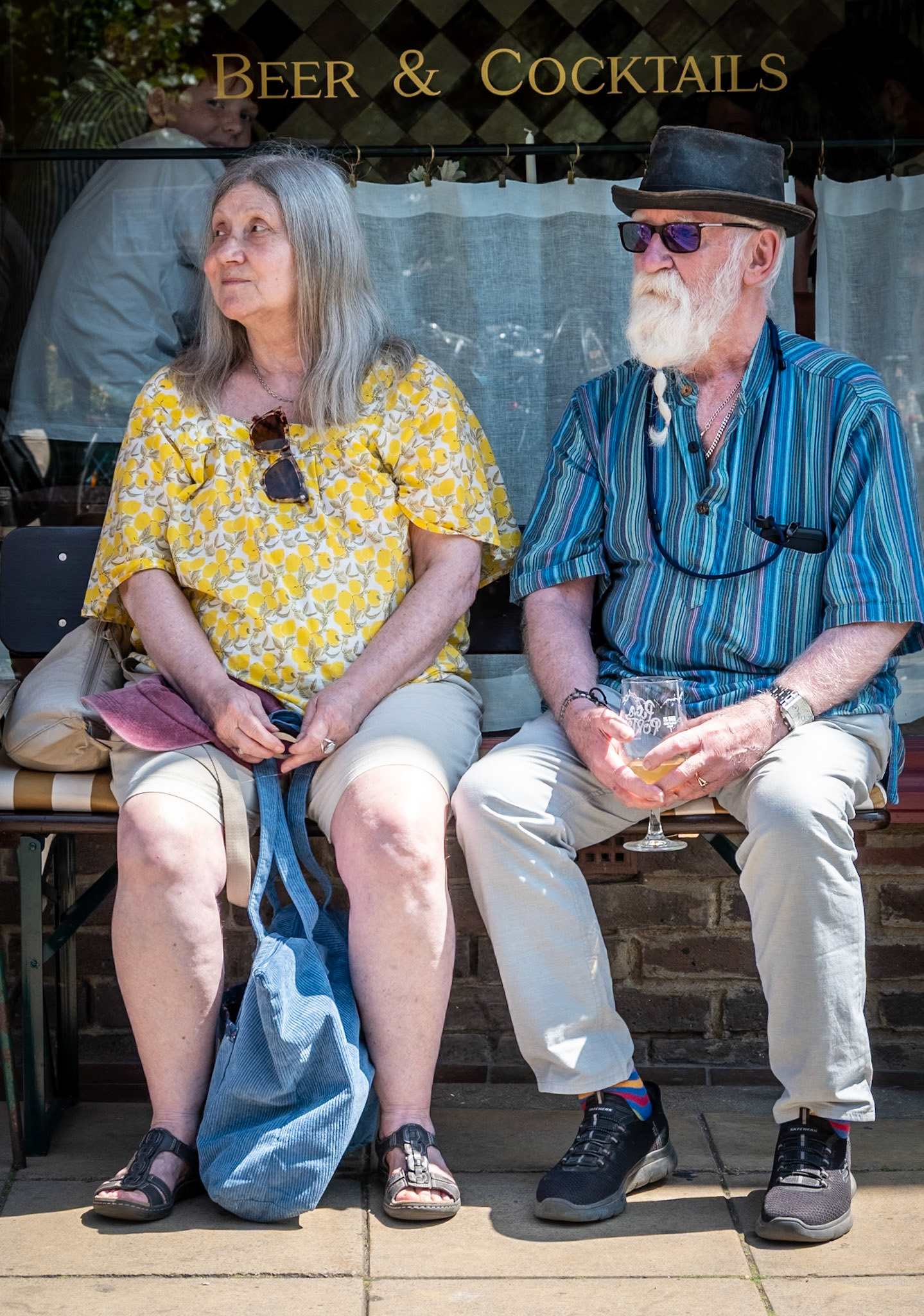 Sherri and Dave enjoying a drink and the music of James Boyd, outside Le Pinardier, Saturday 25th July, 2026. Sherri was formerly in theatre, acting and producing; Dave is a musician. They were visiting from London.